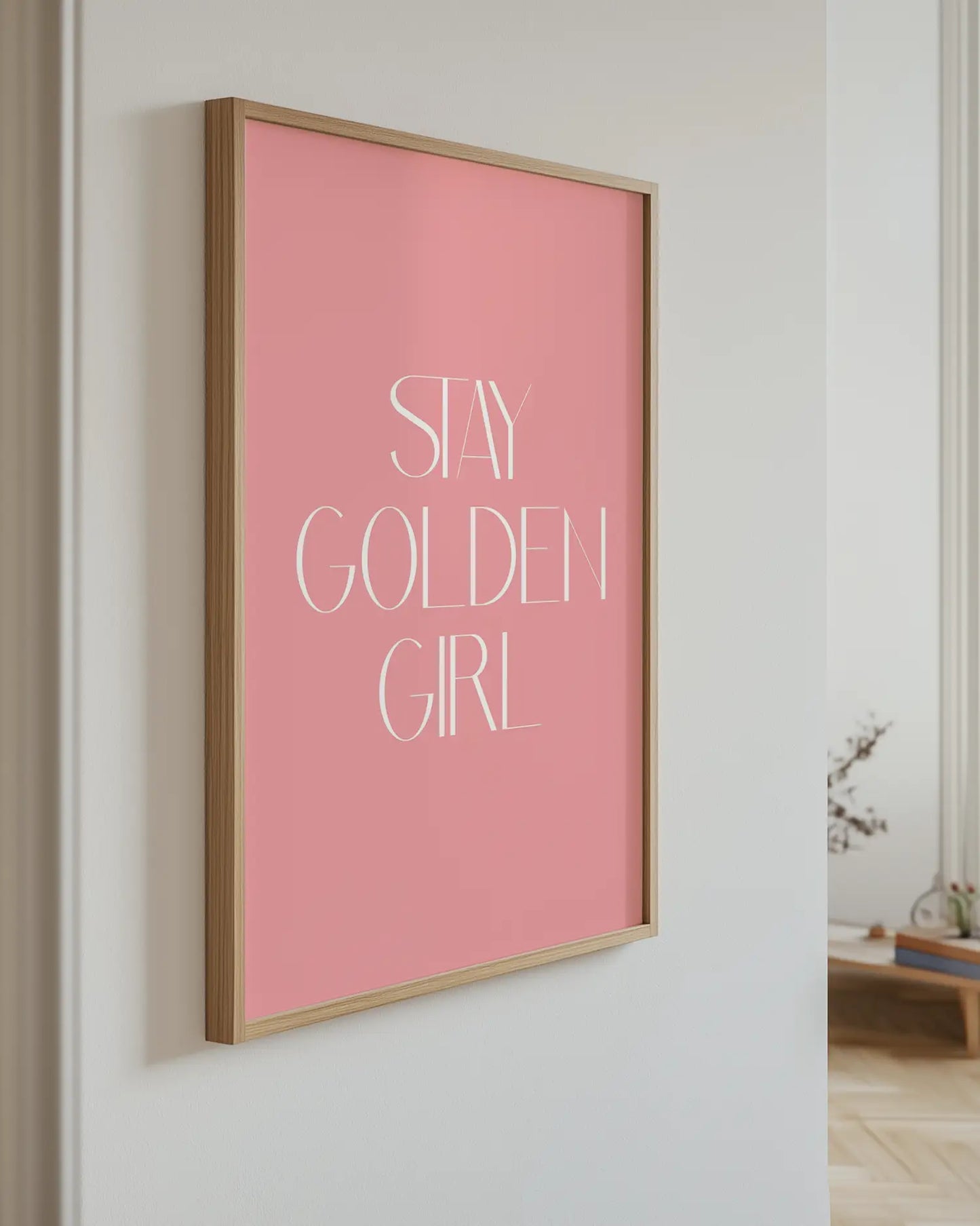 Barnrumstavla med texten “Stay Golden Girl” upphängd på vägg i ekram. En stilren och inspirerande detalj med modern design.