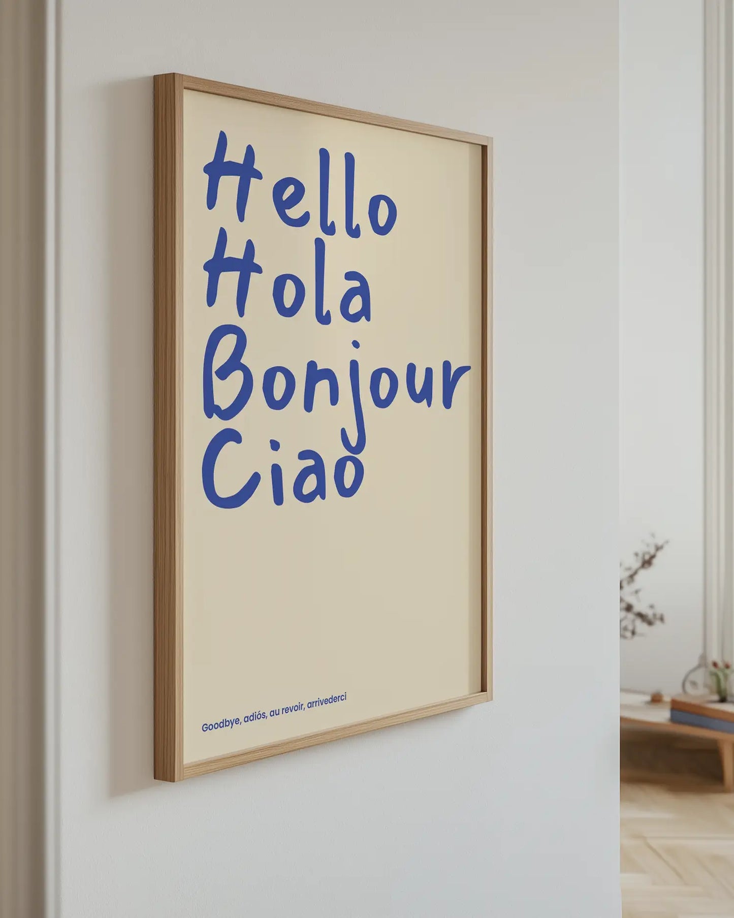 Barntavla med blå text “Hello Hola Bonjour Ciao” upphängd på vägg med ekram. En stilren och livlig väggdekoration.