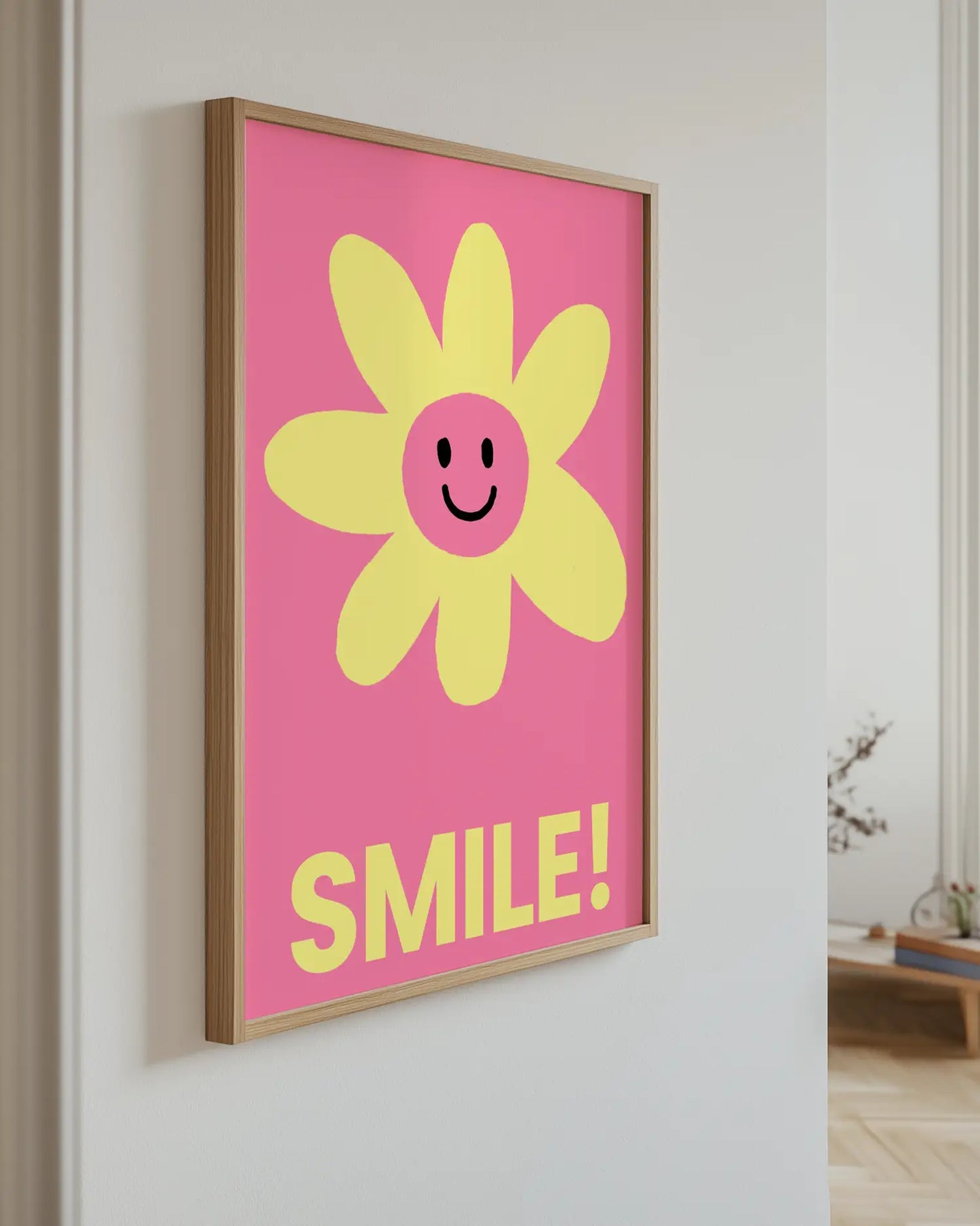 Barntavla med rosa bakgrund och texten “SMILE!” i gult upphängd på vägg med ekram. En lekfull och glad väggdekoration.