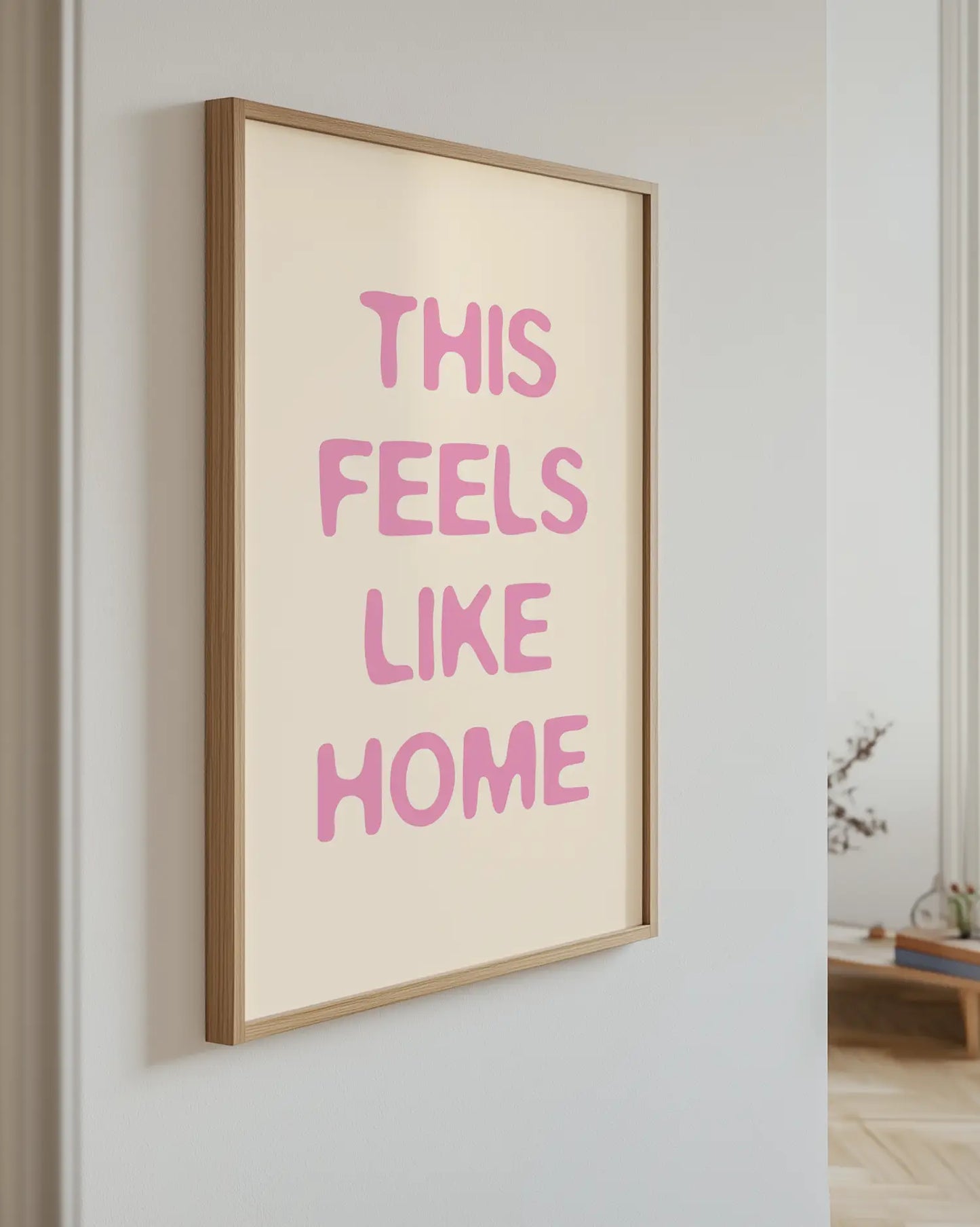 Barntavla med texten “This Feels Like Home” i rosa upphängd på vägg med ekram. En modern och varm väggdekoration med mjuk energi.
