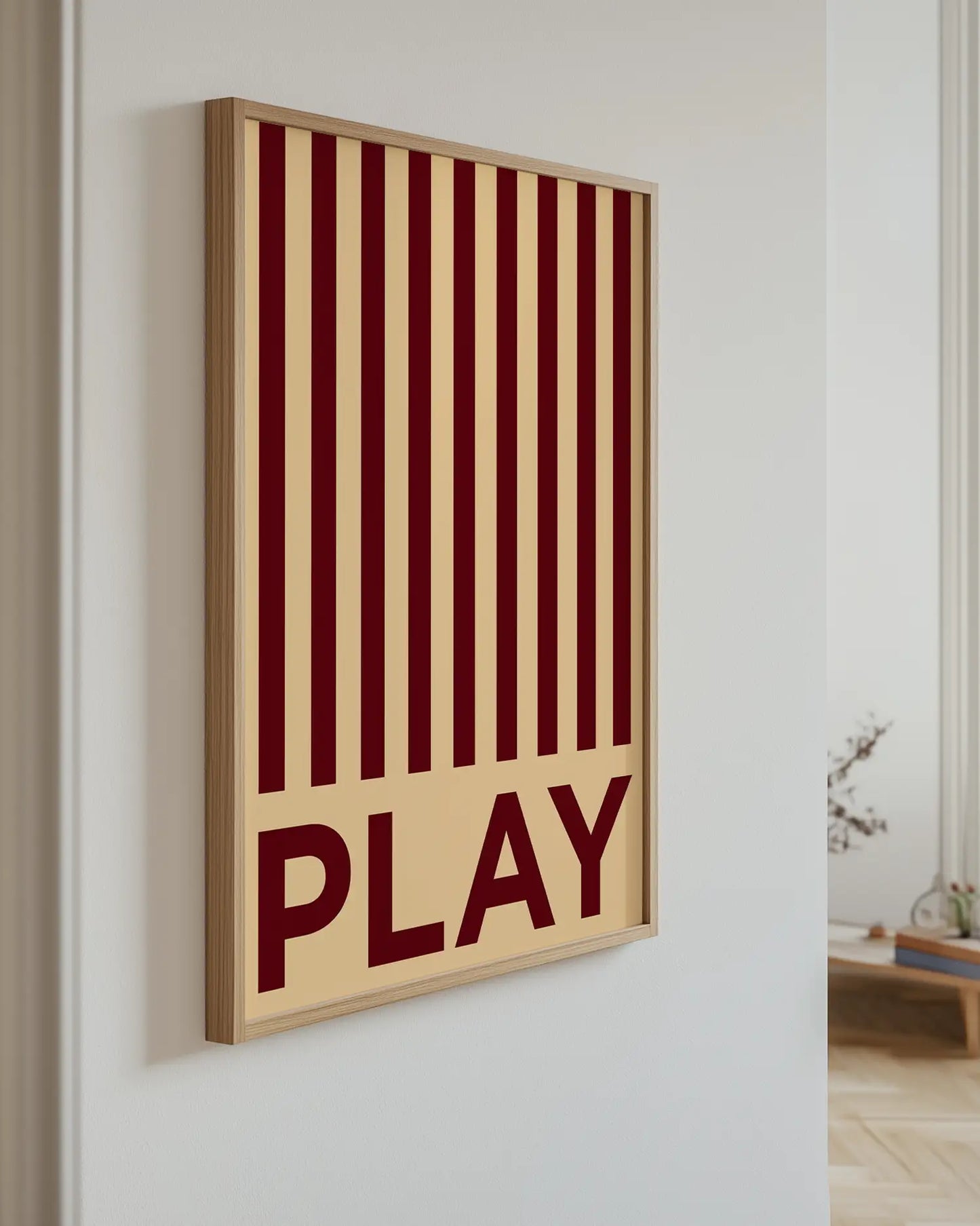 Barntavla med mörkröda ränder och texten “PLAY” upphängd på vägg med ekram. En trendig och färgstark detalj i barnrummet.