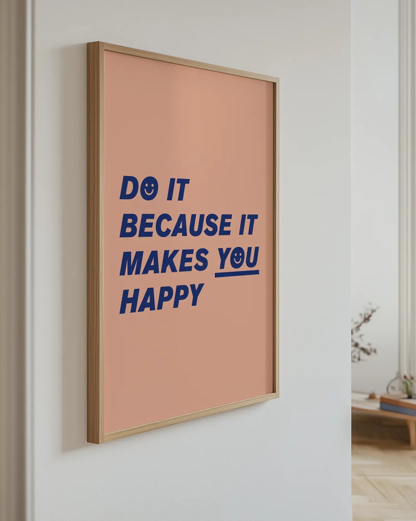 Barntavla med blå text “Do it because it makes you happy” upphängd på vägg med ekram. En modern och motiverande väggdekoration i varma färger.