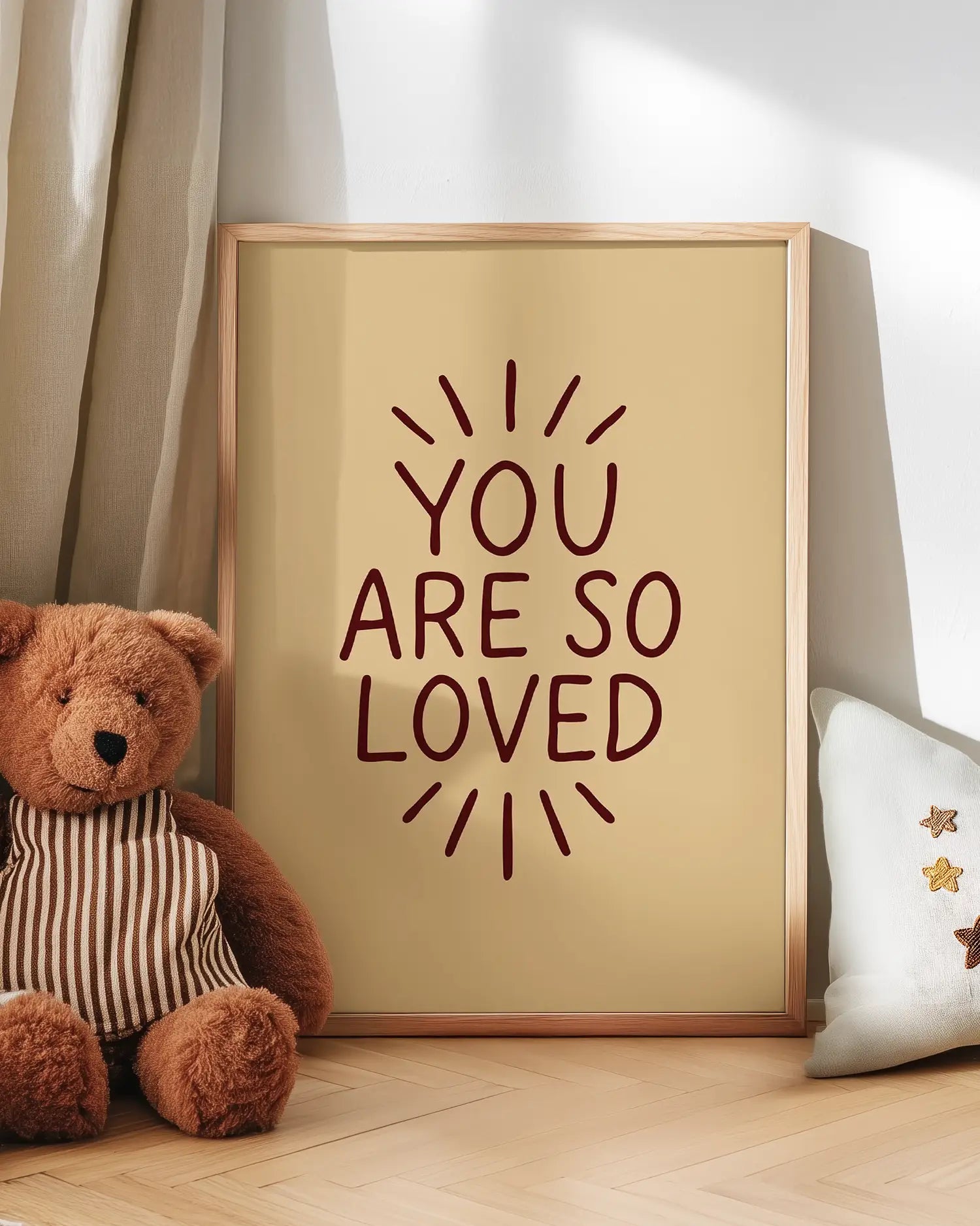 Barntavla med texten ”YOU ARE SO LOVED” på beige bakgrund, lutad mot vägg bredvid nalle. En mjuk och kärleksfull dekoration som skapar trygg stämning.