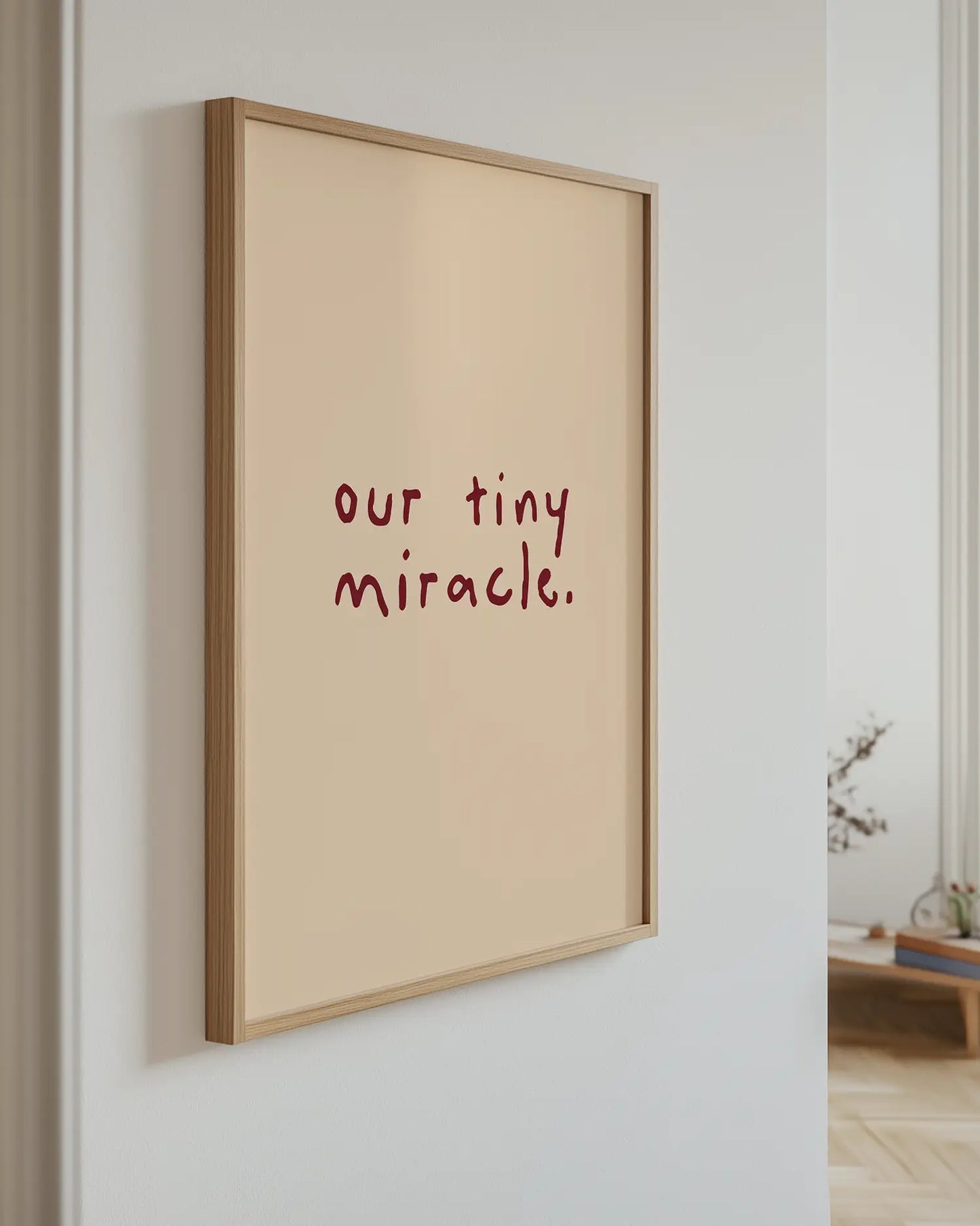 Barnrumstavla med "our tiny miracle." på beige bakgrund, upphängd på vägg i ekram. En enkel och harmonisk dekoration som skapar ro i rummet.