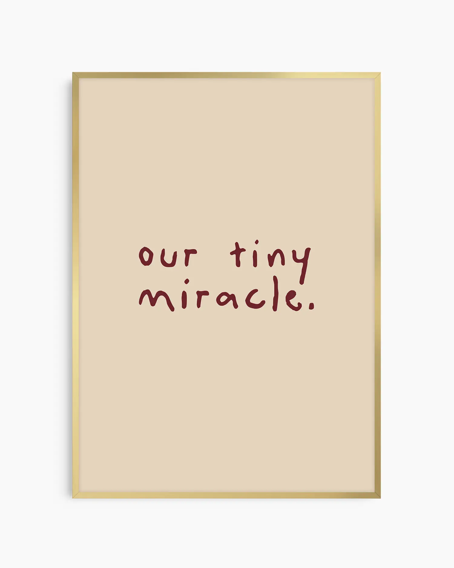 Barntavla med texten "our tiny miracle." i vinröd skrift på beige bakgrund, inramad i guld aluminiumram. En elegant och stillsam dekoration med varm känsla.