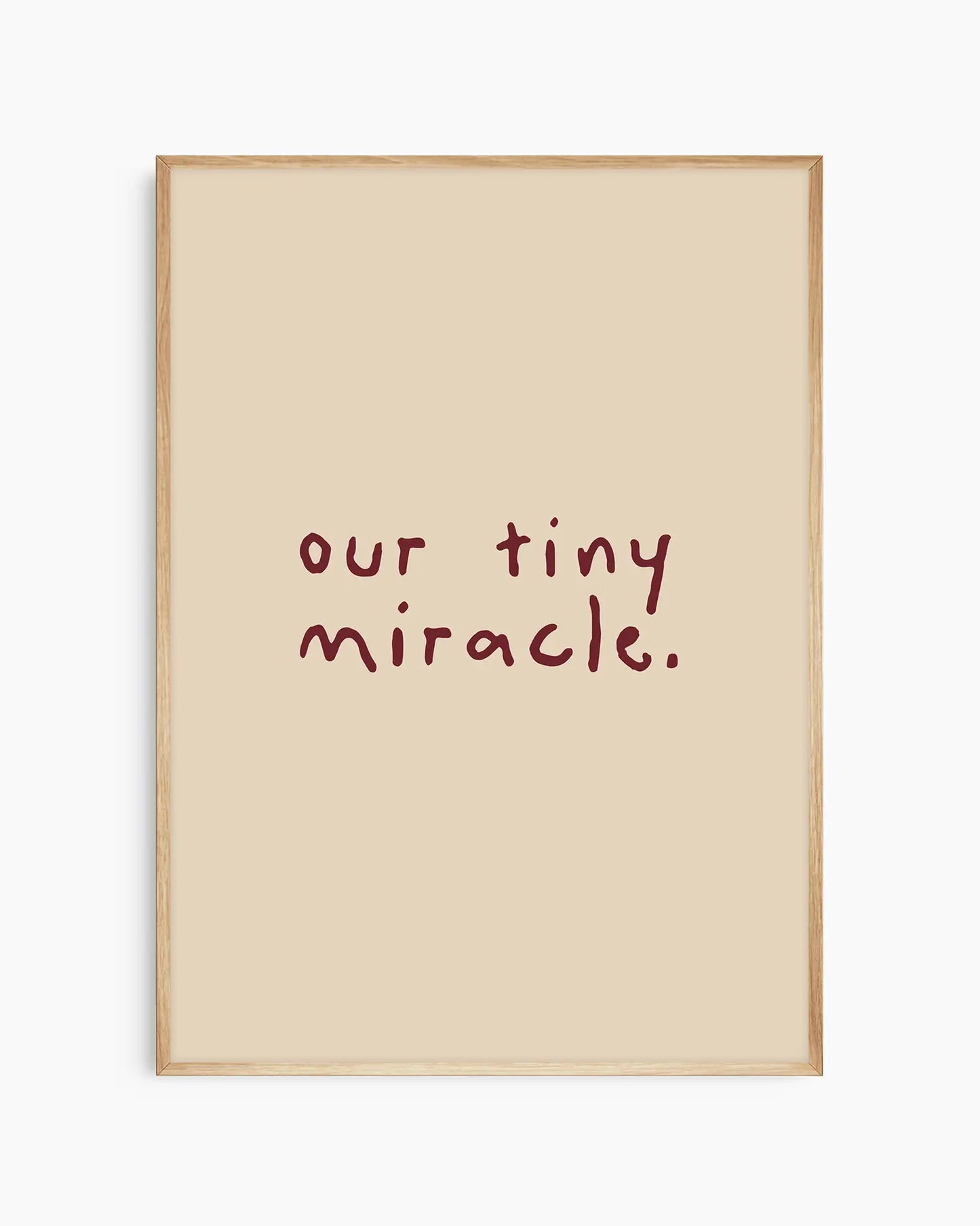 Barnrumstavla med "our tiny miracle." skrivet i vinrött på beige bakgrund, inramad i ekram. En naturlig och mjuk väggdetalj som passar i alla barnrum.