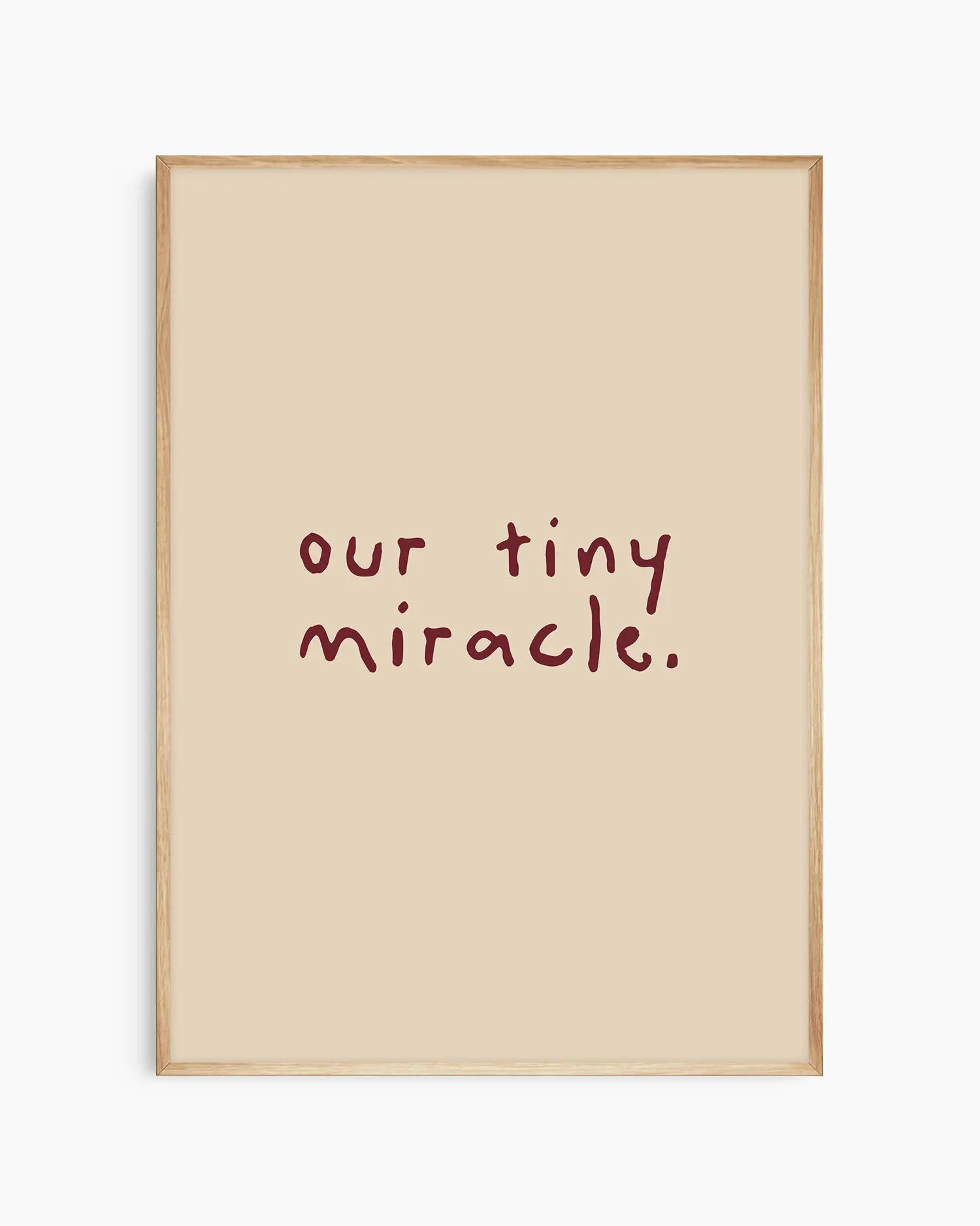Barnrumstavla med "our tiny miracle." skrivet i vinrött på beige bakgrund, inramad i ekram. En naturlig och mjuk väggdetalj som passar i alla barnrum.