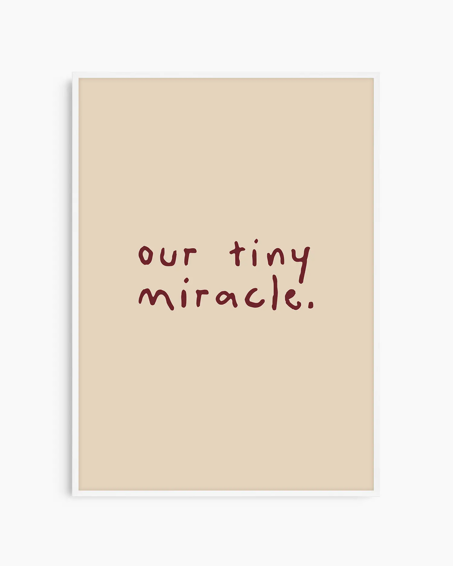 Barntavla med den vinröda texten "our tiny miracle." på beige bakgrund, inramad i vit träram. En ljus och minimalistisk dekoration med fin känsla.