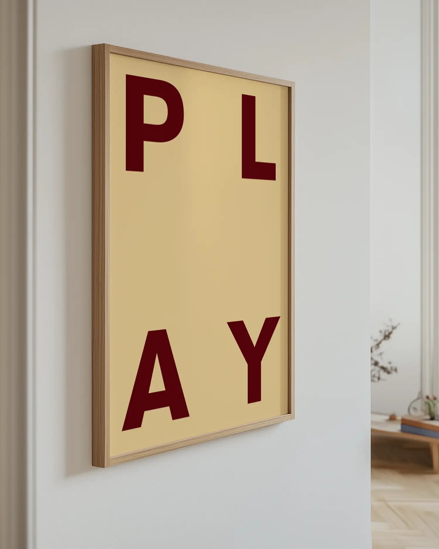 Barnrumstavla med PLAY i mörkröd text upphängd på vägg i ekram. En stilren och modern dekoration som passar i lekfulla miljöer.