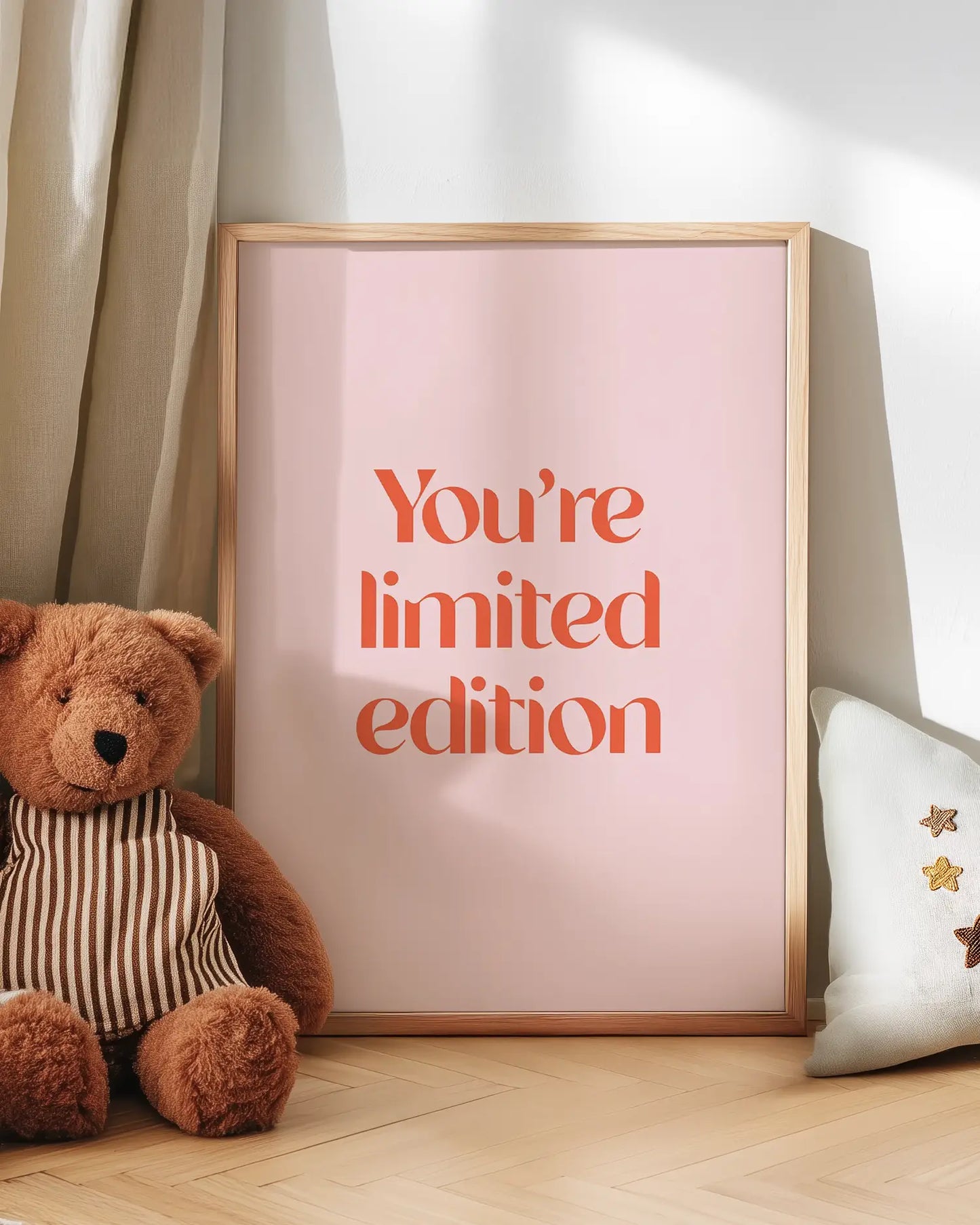 Barntavla med texten “You’re Limited Edition” lutad mot vägg bredvid nalle. En charmig och upplyftande väggdekoration för barnrummet.