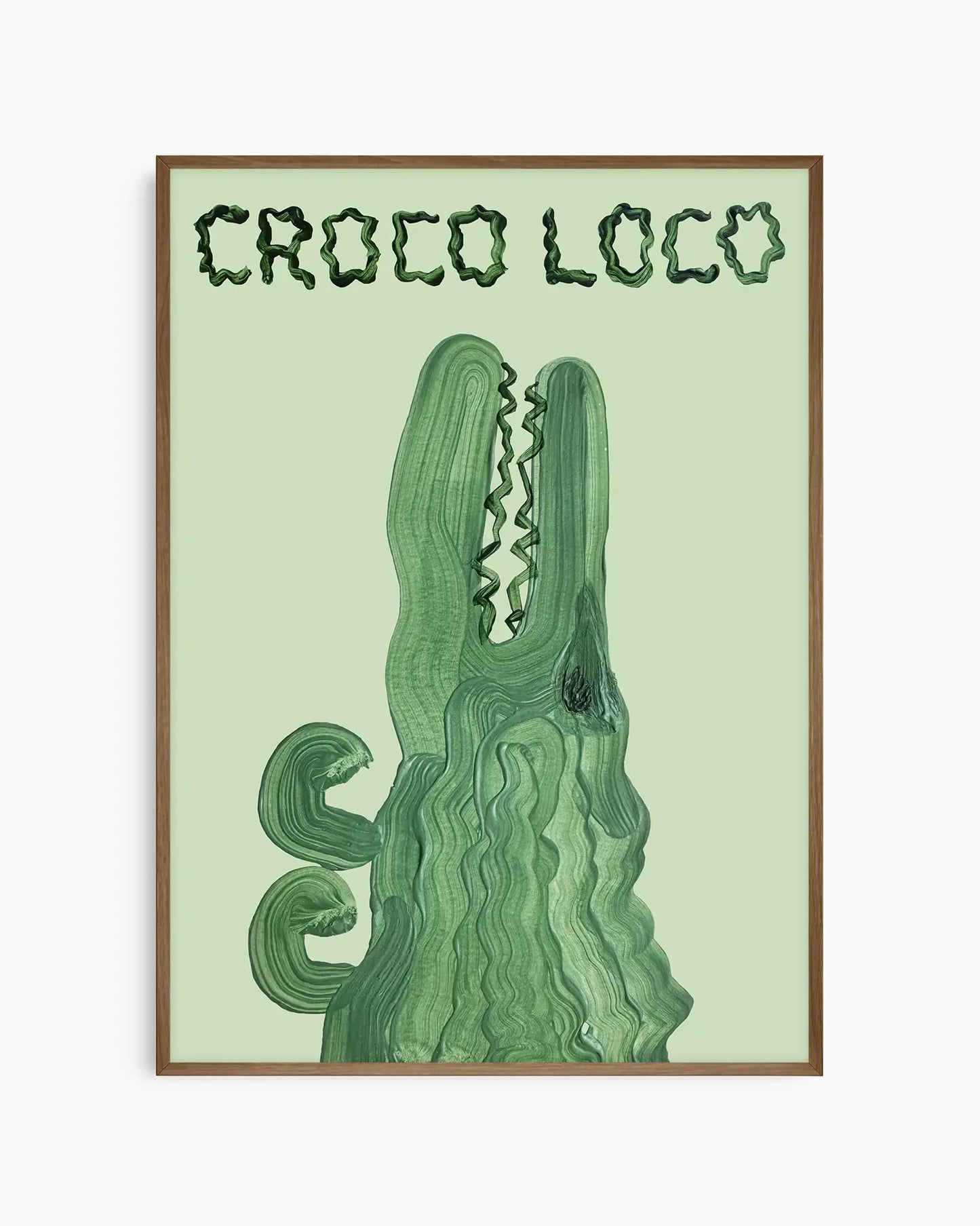 Barnrumstavla med grön krokodil och lekfull text “CROCO LOCO” på ljusgrön bakgrund, inramad i träram i mörk ek. En charmig och busig väggdekoration.