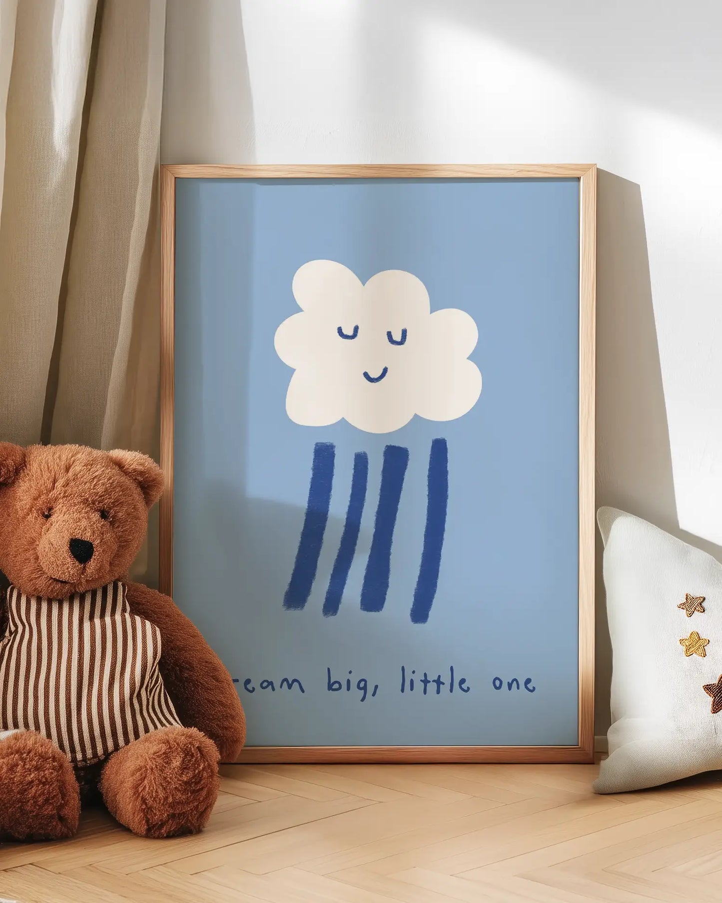 Barntavla med vitt moln med sovande ansikte och texten “dream big, little one” lutad mot vägg bredvid nalle. En mjuk och trygg väggdekoration för barnrummet.