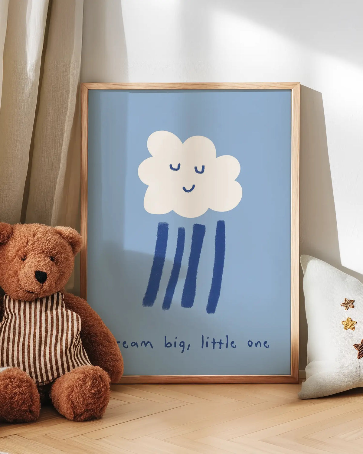 Barntavla med vitt moln med sovande ansikte och texten “dream big, little one” lutad mot vägg bredvid nalle. En mjuk och trygg väggdekoration för barnrummet.