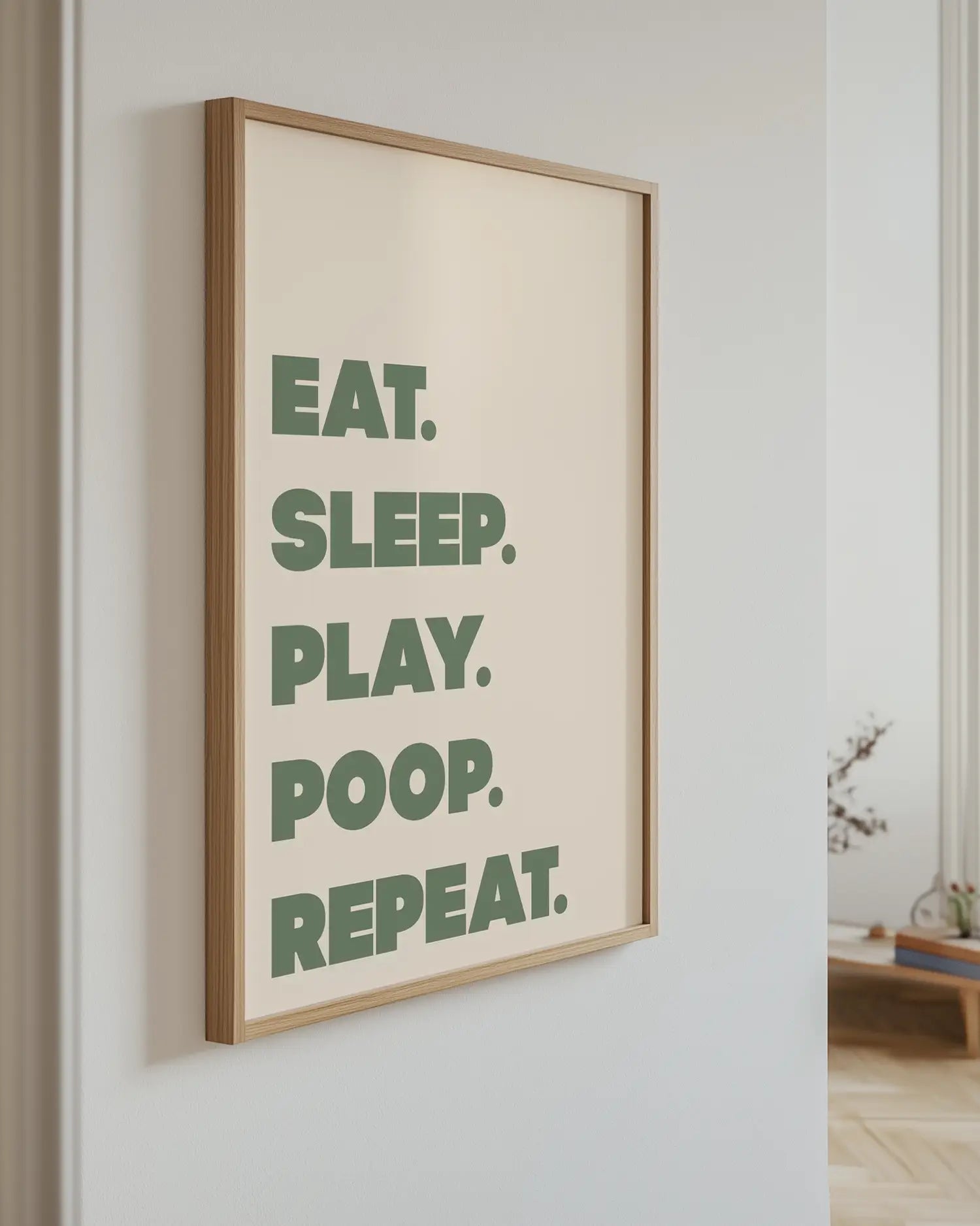 Barntavla med texten “EAT. SLEEP. PLAY. POOP. REPEAT.” i grön färg upphängd på vägg med ekram. En humoristisk och charmig väggdekoration.