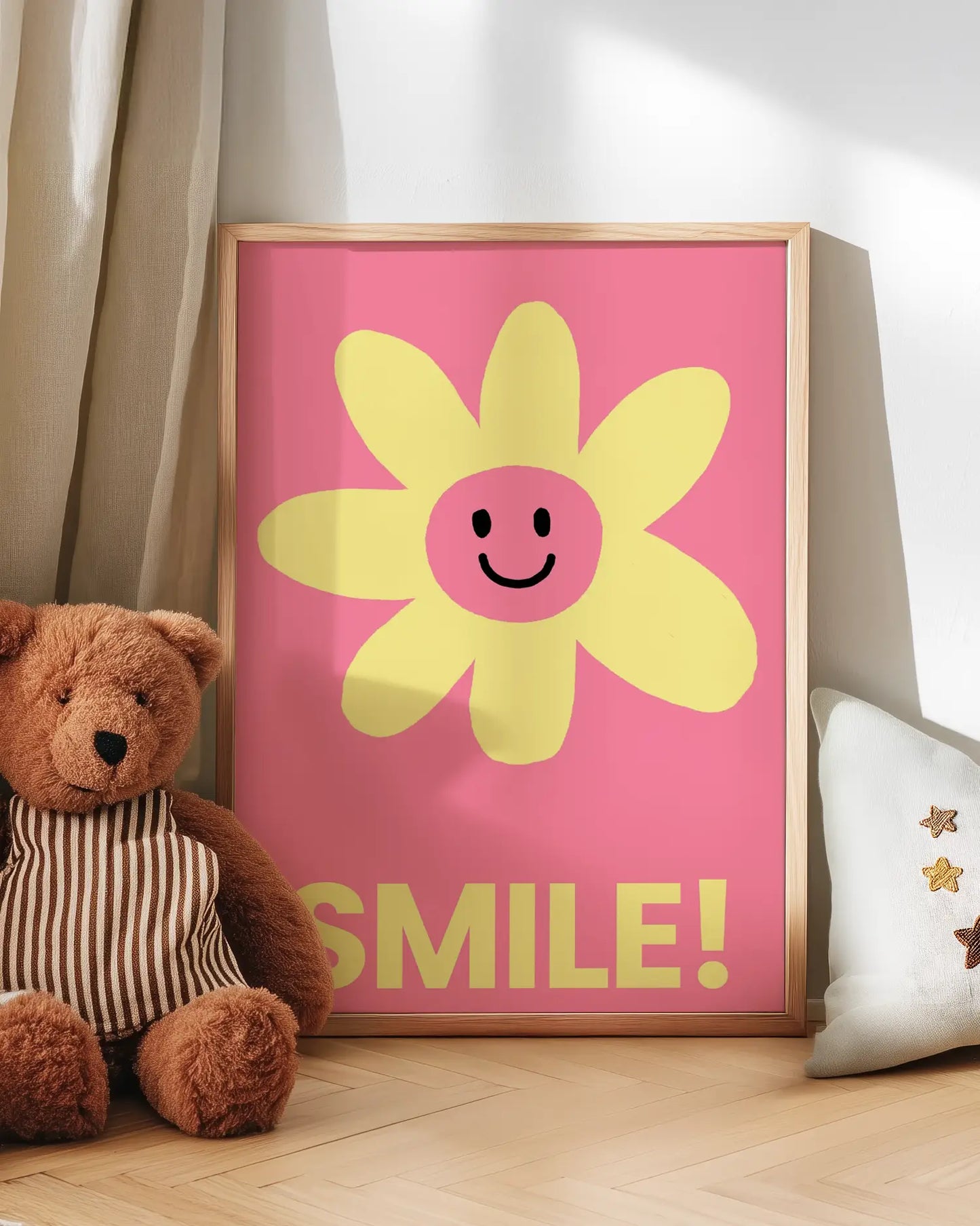 Barntavla med gul blomma med leende ansikte och texten “SMILE!” på rosa bakgrund lutad mot vägg bredvid nalle. En söt och positiv väggdekoration som passar perfekt i barnrummet.