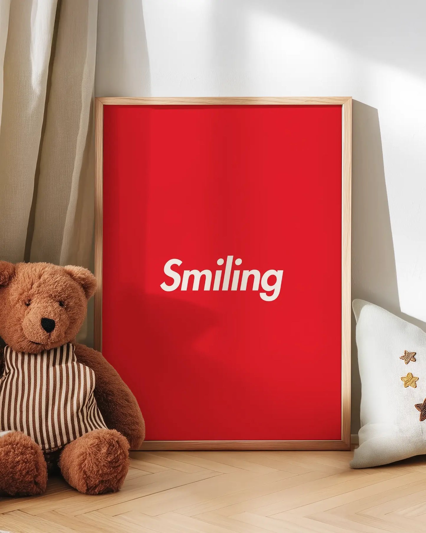 Barntavla med ordet “Smiling” i vitt på röd bakgrund lutad mot vägg bredvid nalle. En glad och charmig väggdekoration som passar perfekt i barnrummet.