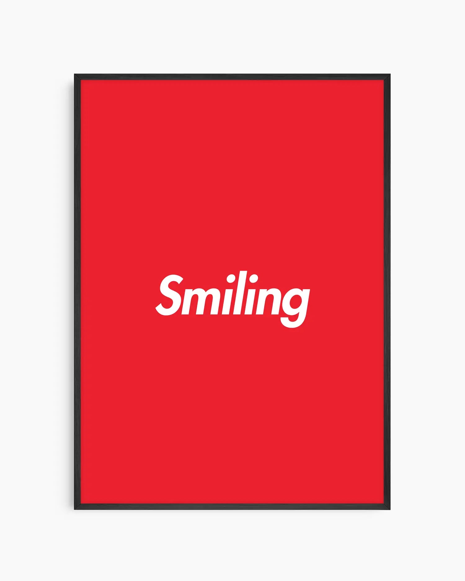 Barntavla med ordet “Smiling” i vitt på starkt röd bakgrund, inramad i svart träram. En enkel och färgglad väggdekoration med positiv energi.
