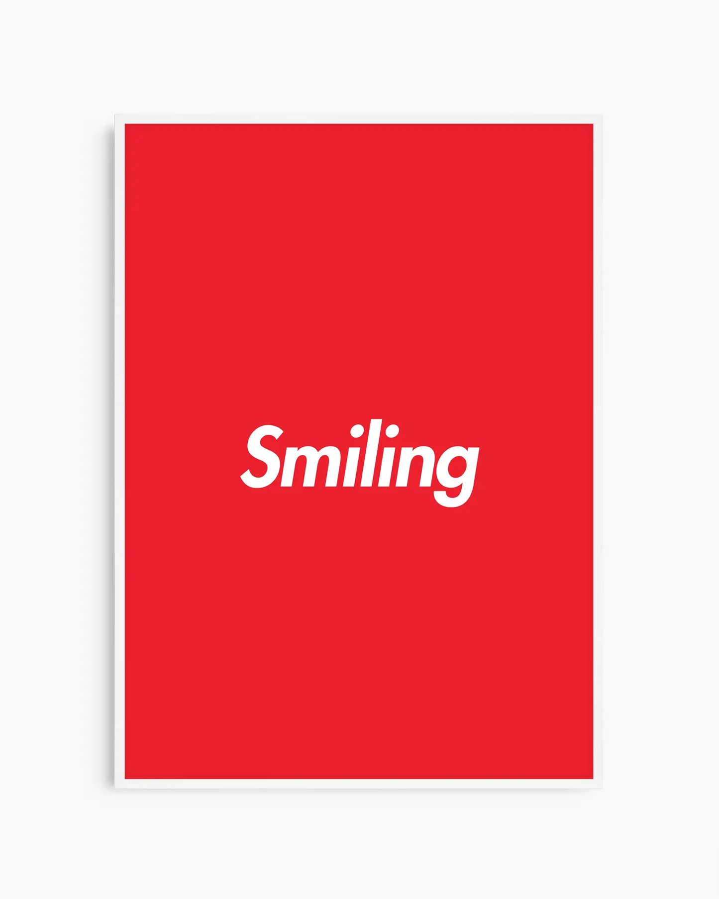 Barntavla med texten “Smiling” i vitt på röd bakgrund, inramad i vit träram. En enkel och färgglad väggdekoration med positiv budskap.