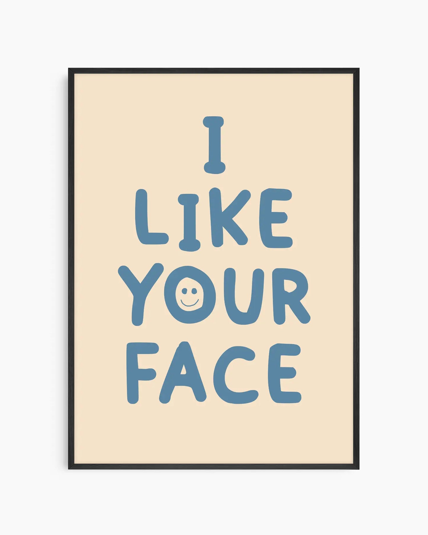 Barntavla med texten “I LIKE YOUR FACE” i blått med ett litet smiley-ansikte på beige bakgrund, inramad i svart träram. En glad och lekfull väggdekoration.