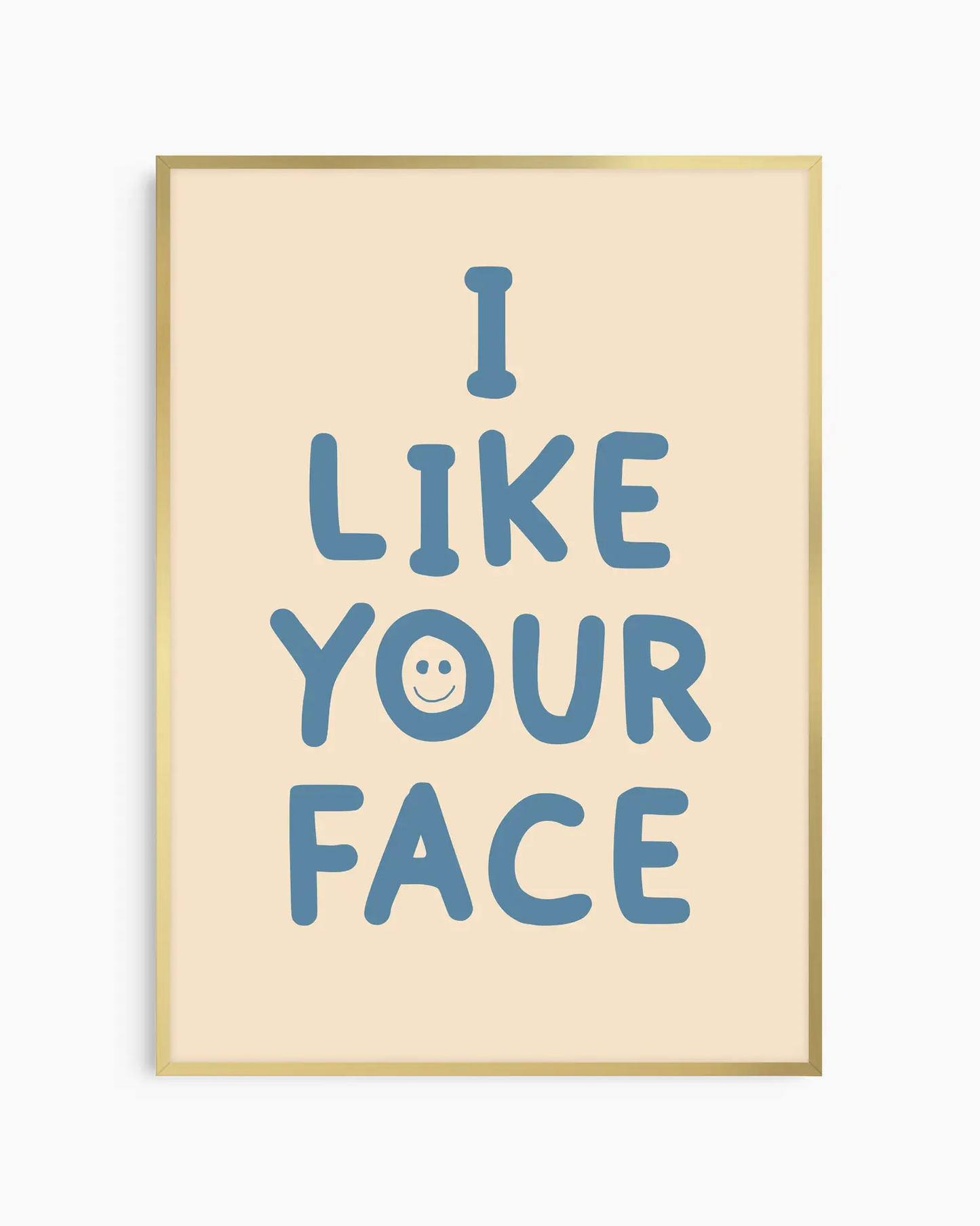 Barntavla med texten “I LIKE YOUR FACE” i blått med smiley på beige bakgrund, inramad i guld aluminiumram. En positiv och färgglad väggdekoration för barnrummet.