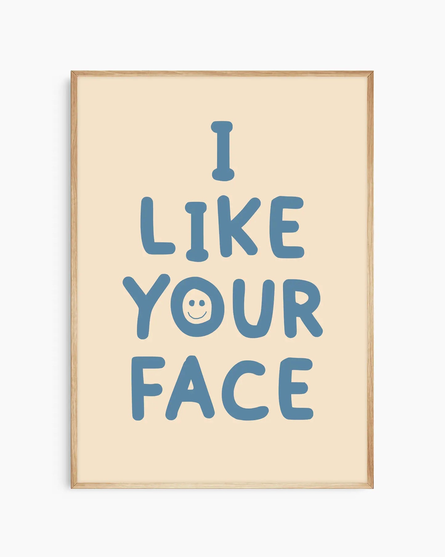 Barntavla med blå text “I LIKE YOUR FACE” och smiley på ljus beige bakgrund, inramad i ekram. En söt och modern väggdekoration som sprider glädje.