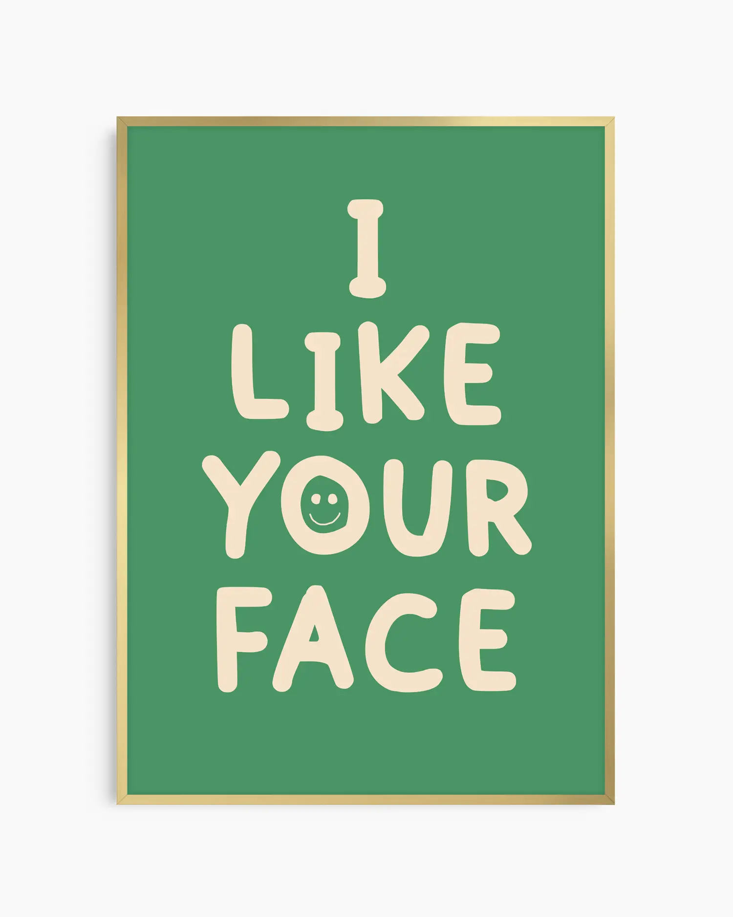 Barntavla med grön bakgrund och beige text “I LIKE YOUR FACE” med smiley, inramad i guld aluminiumram. En positiv och lekfull väggdekoration som sprider glädje.