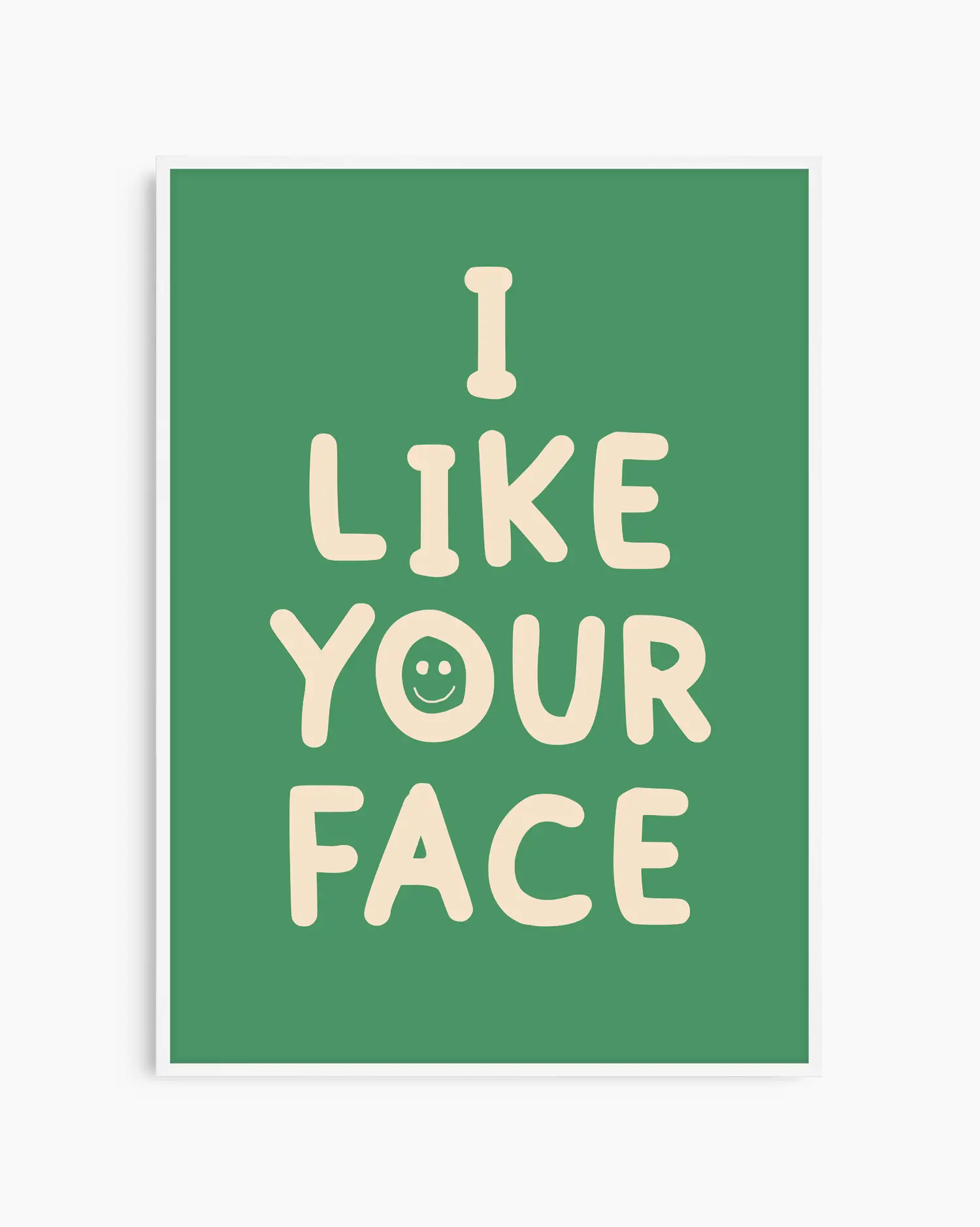 Barntavla med grön bakgrund och beige text “I LIKE YOUR FACE” i rundad font, inramad i vit träram. En lekfull och kärleksfull väggdekoration.