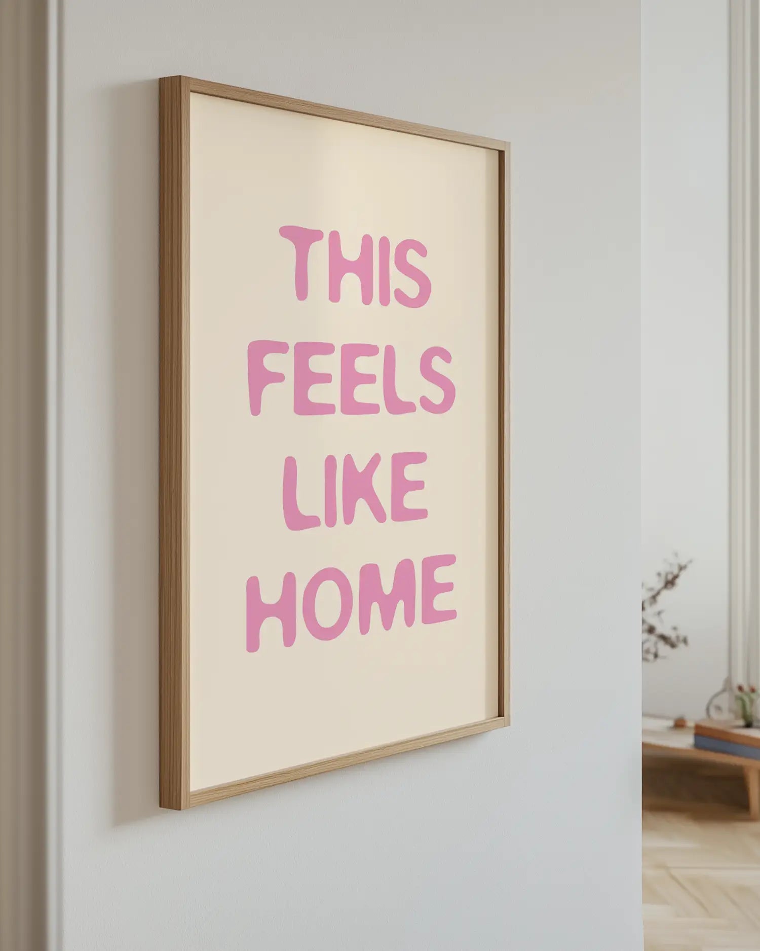 Barntavla med texten “This Feels Like Home” i rosa upphängd på vägg med ekram. En modern och varm väggdekoration med mjuk energi.