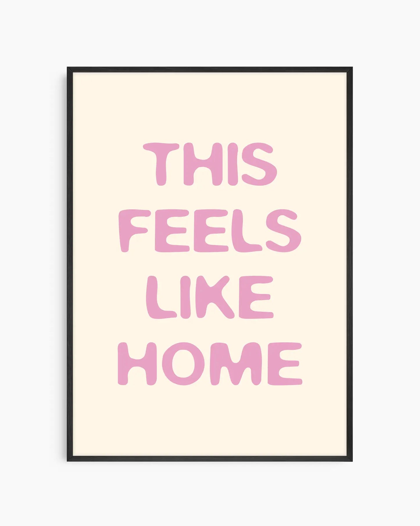 Barntavla med texten “This Feels Like Home” i mjuk rosa ton på ljus bakgrund, inramad i svart träram. En varm och trygg väggdekoration med kärleksfull känsla.