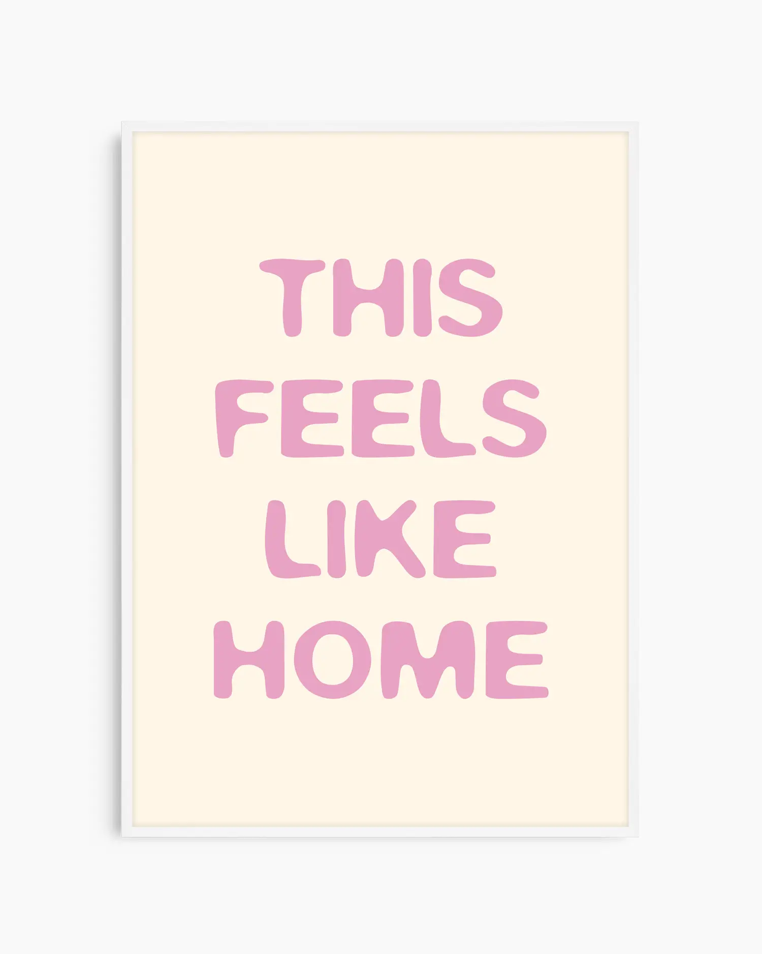 Barntavla med texten “This Feels Like Home” i ljusrosa ton på beige bakgrund, inramad i vit träram. En mjuk och söt väggdekoration med hemtrevlig känsla.