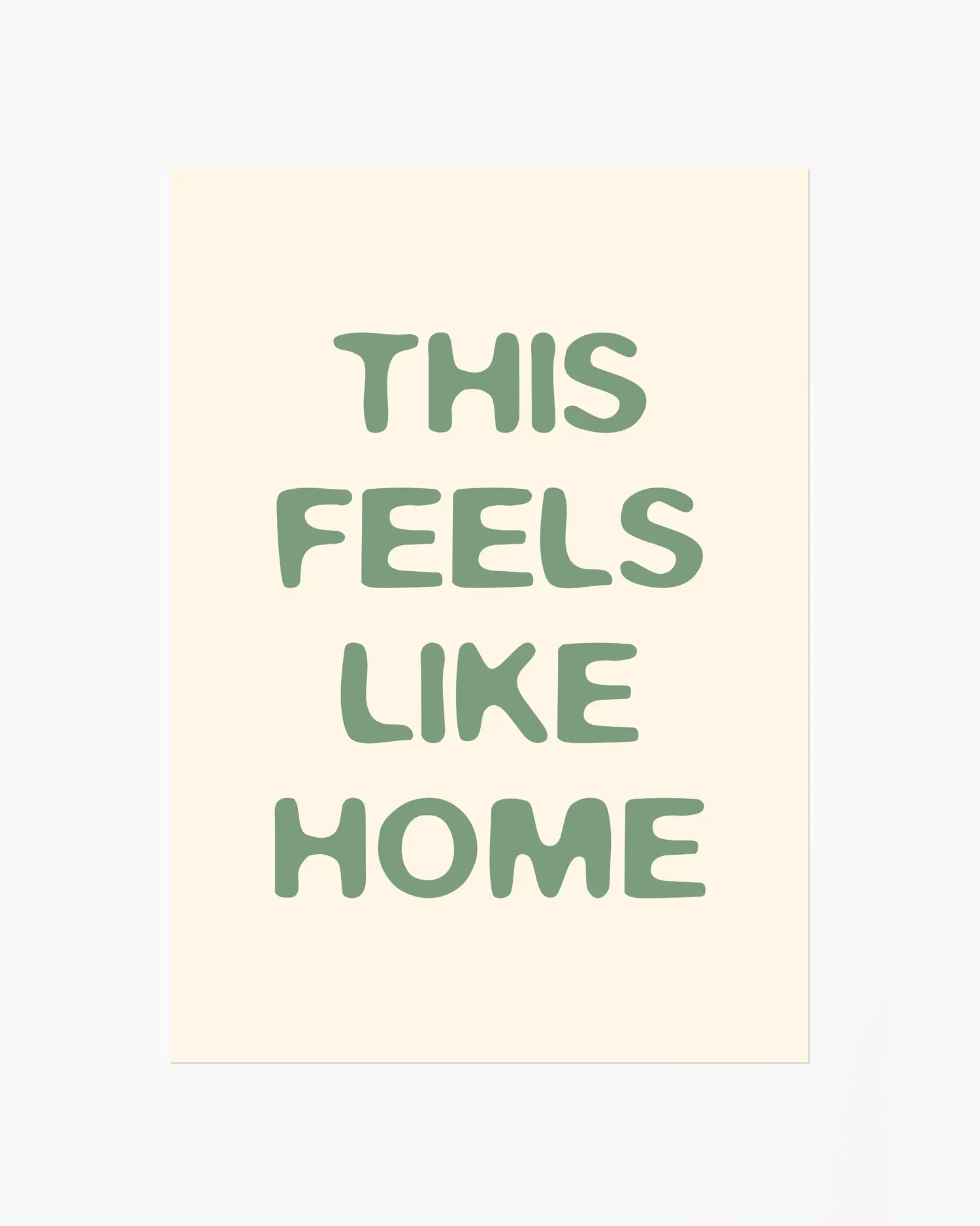 Barntavla med texten “This Feels Like Home” i mjuk grön färg på ljus bakgrund. En enkel och varm design med hemtrevlig känsla.