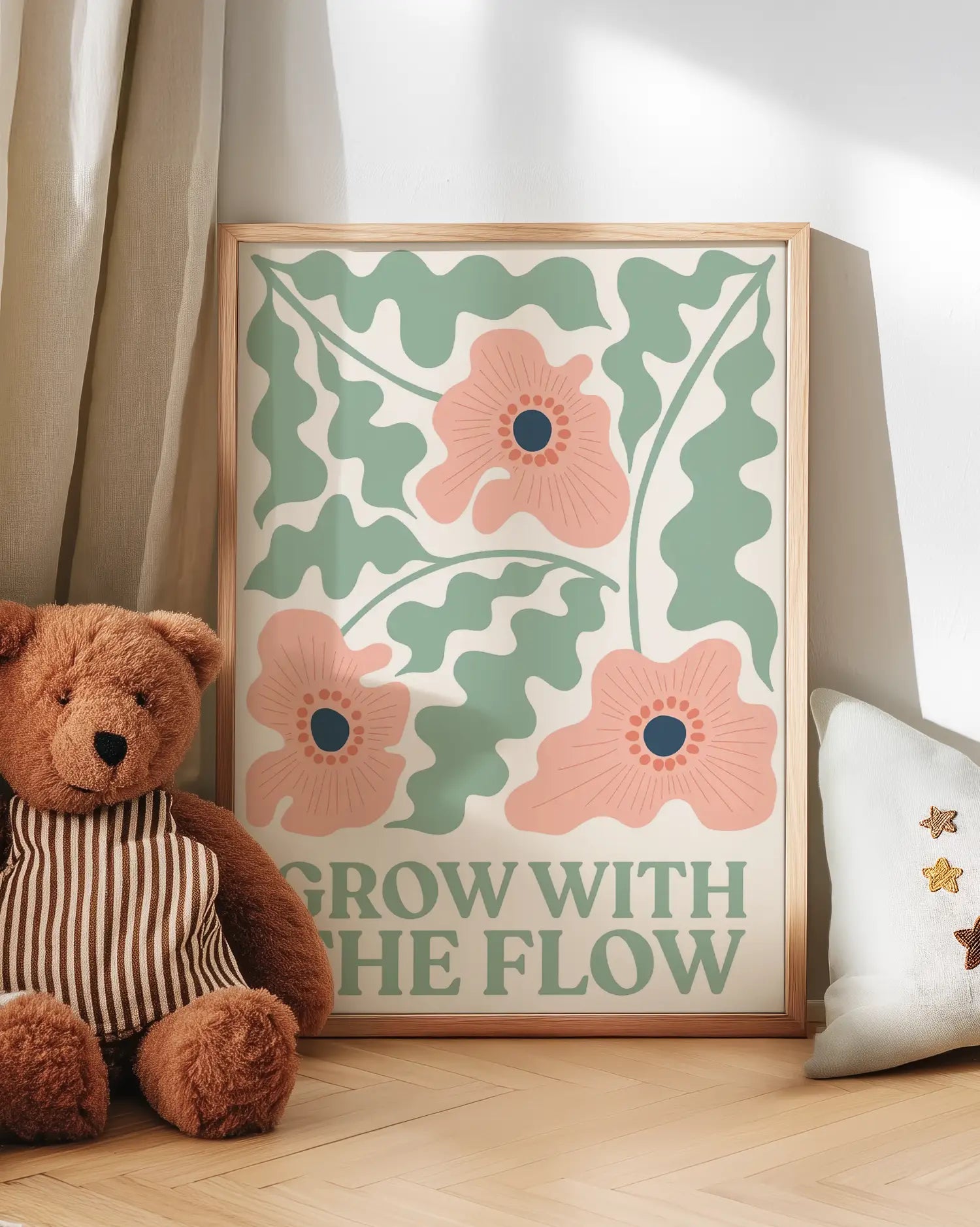 Barntavla med illustration av blommor och blad i grönt och rosa lutad mot vägg bredvid nalle. En charmig och inspirerande väggdekoration som sprider lugn.