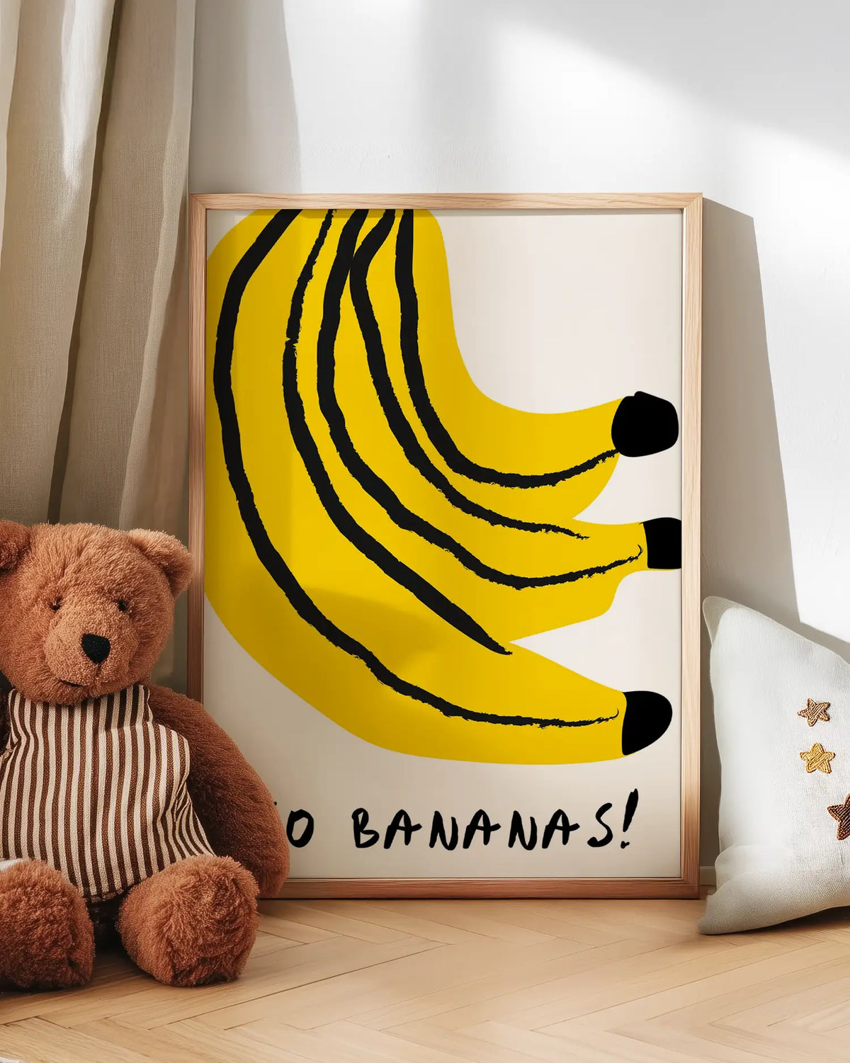 Barntavla med gula bananer och text “Go Bananas!” lutad mot vägg bredvid nalle. En charmig och färgglad väggdekoration som sprider positiv energi.