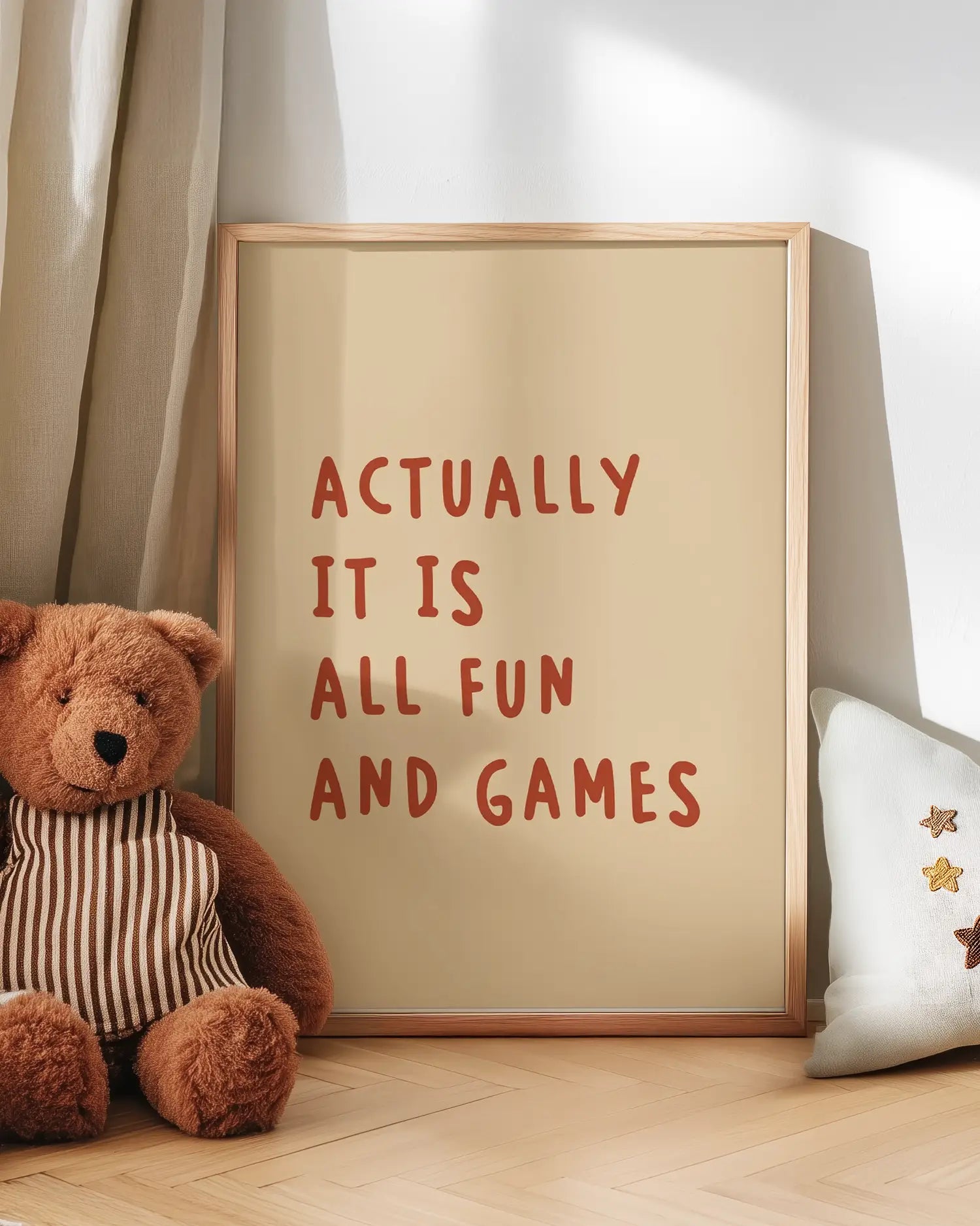 Barntavla med rostbrun text “ACTUALLY IT IS ALL FUN AND GAMES” lutad mot vägg bredvid nalle. En varm och humoristisk detalj som sprider glädje i barnrummet.