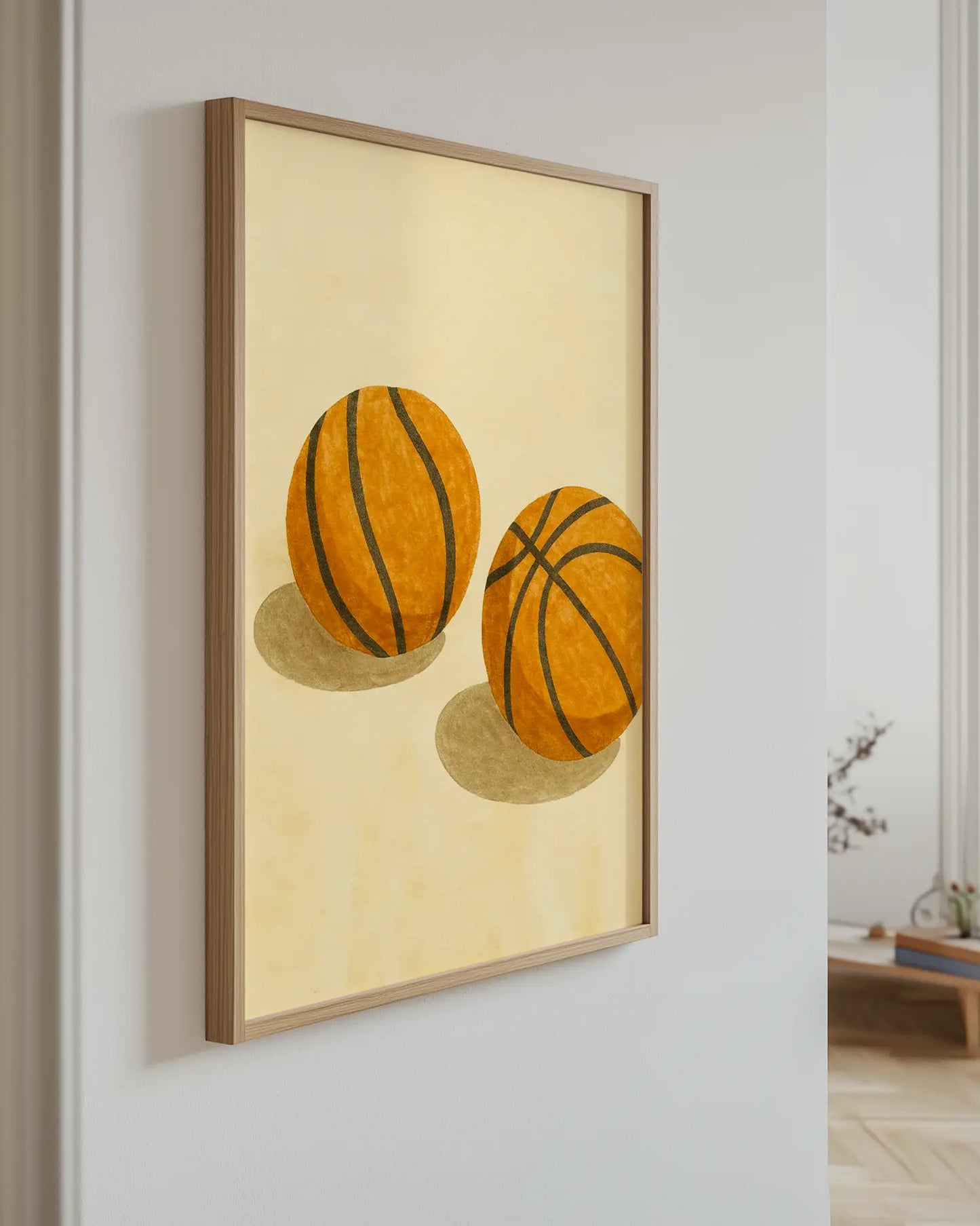 Barntavla med två basketbollar på beige bakgrund, upphängd på vägg med ekram. En lekfull och elegant väggdekoration för sportälskare.