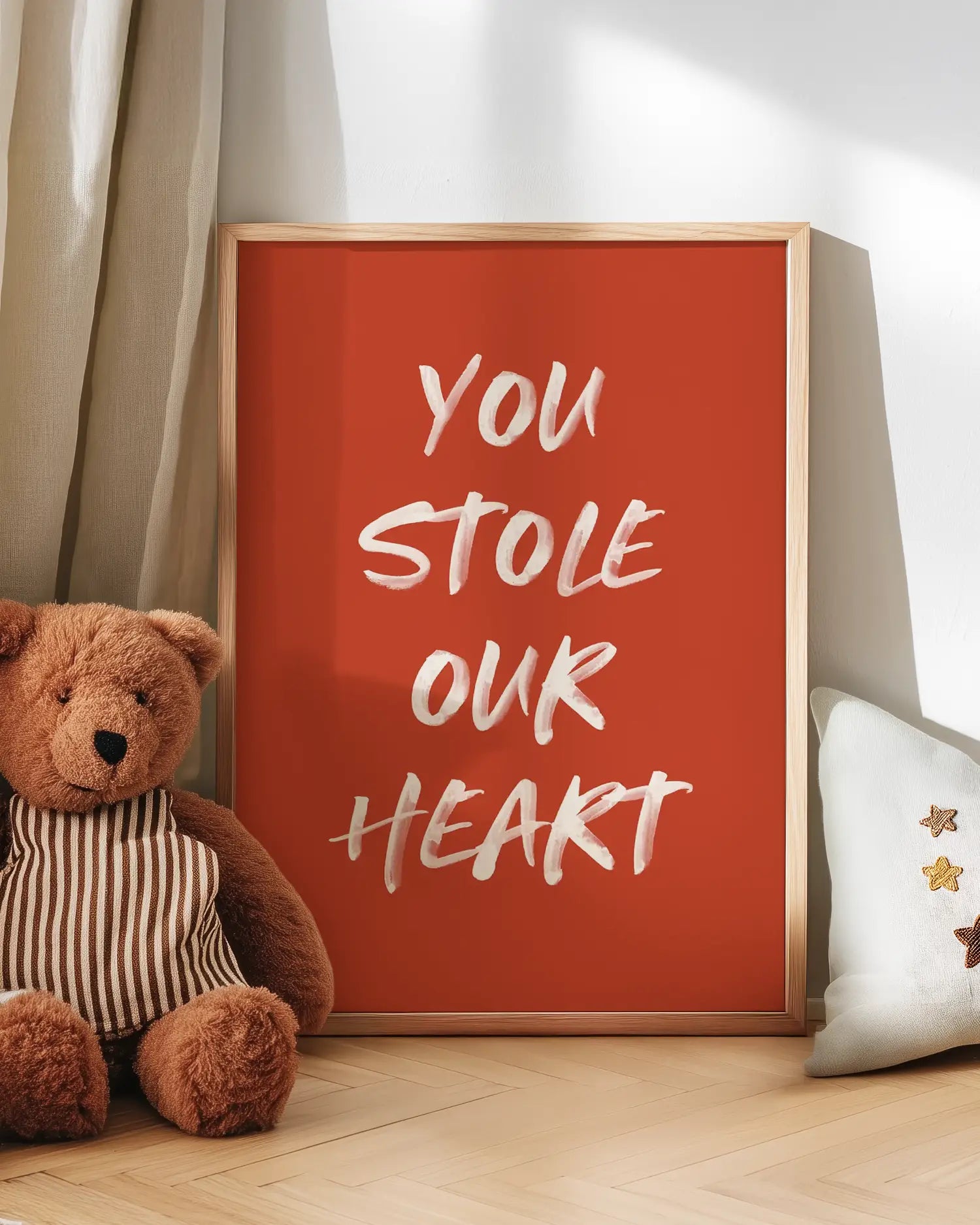 Barntavla med texten "You Stole Our Heart" lutad mot vägg bredvid nalle. En kärleksfull och hemtrevlig scen i barnrummet.