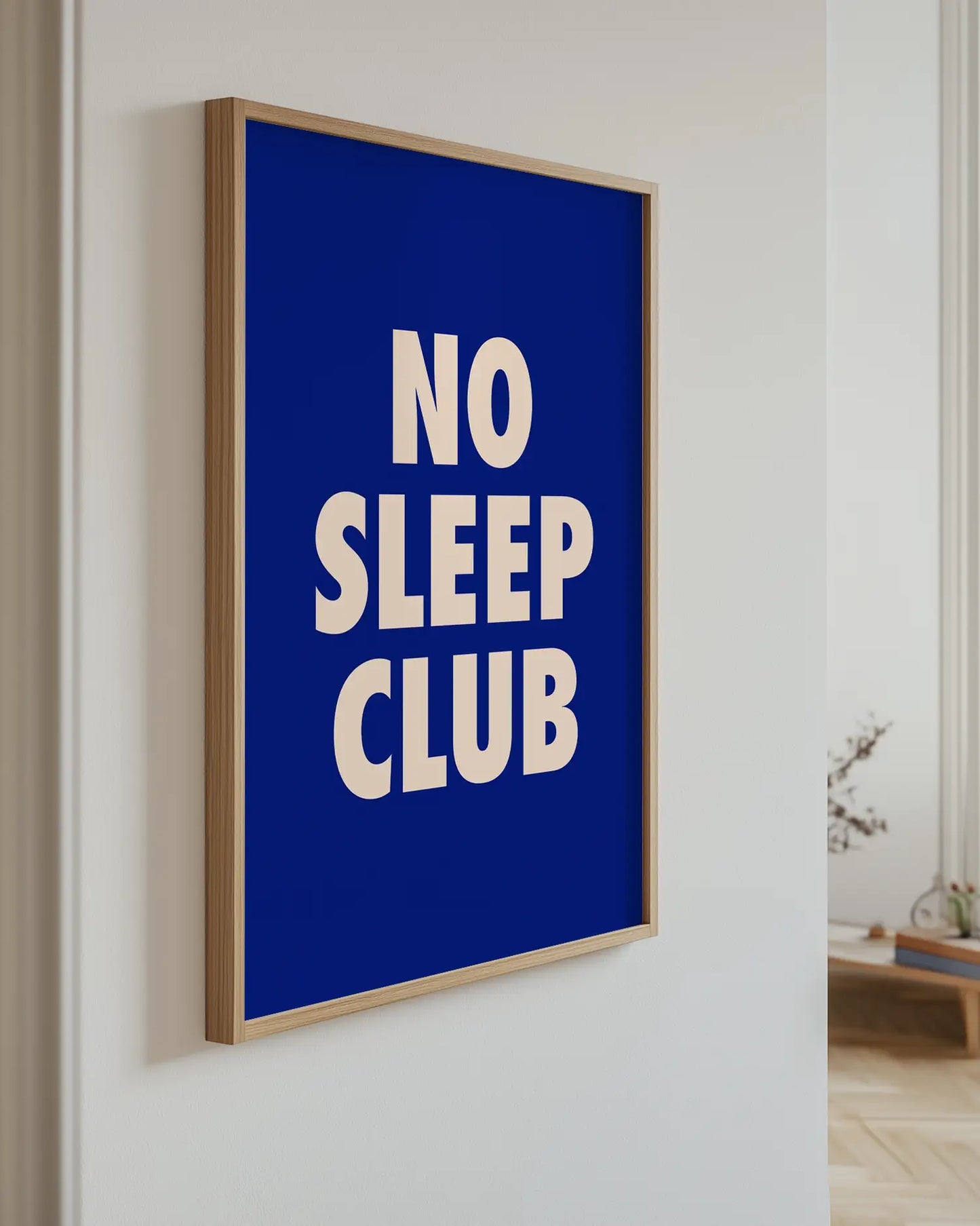Barntavla med texten "No Sleep Club" i ljusrosa mot mörkblå bakgrund, upphängd på vägg med ekram. En stilren och modern detalj som sprider humor.