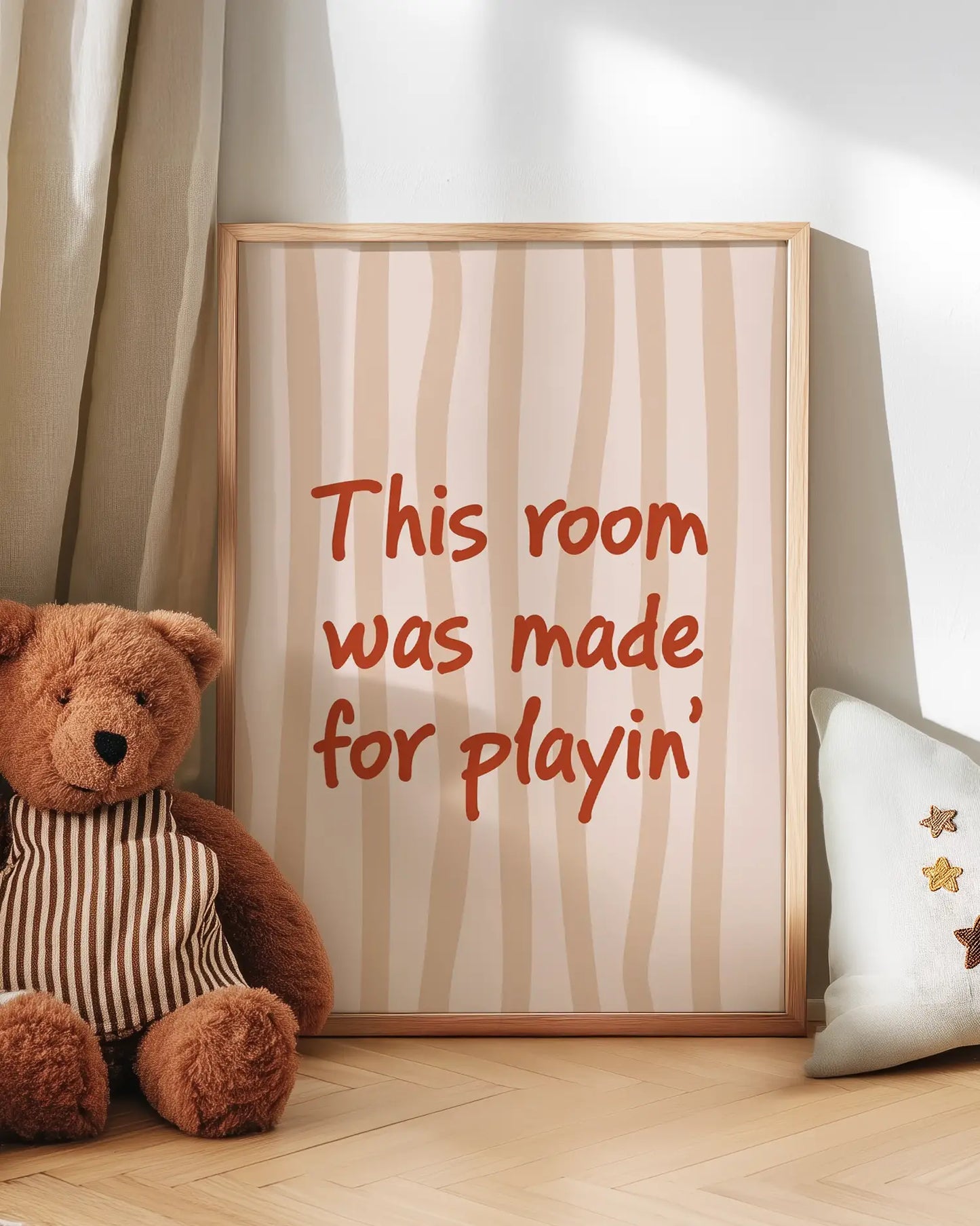 Barntavla med texten "This room was made for playin’" lutad mot vägg bredvid en nalle. En söt och lekfull scen som sprider glädje och värme.