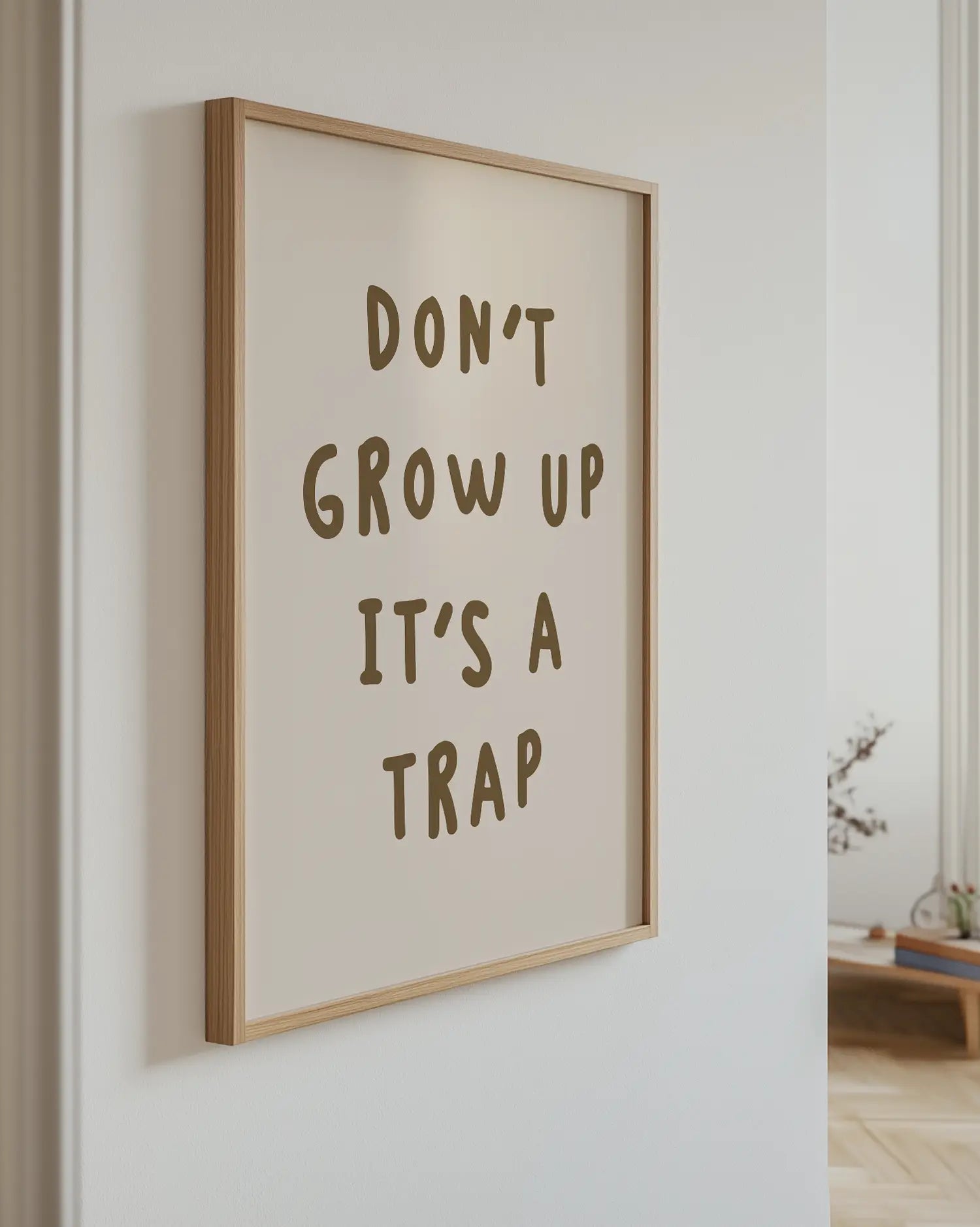 Inramad barntavla med texten “DON’T GROW UP IT’S A TRAP”, hängandes på väggen som en lekfull och humoristisk detalj i barnrummet.
