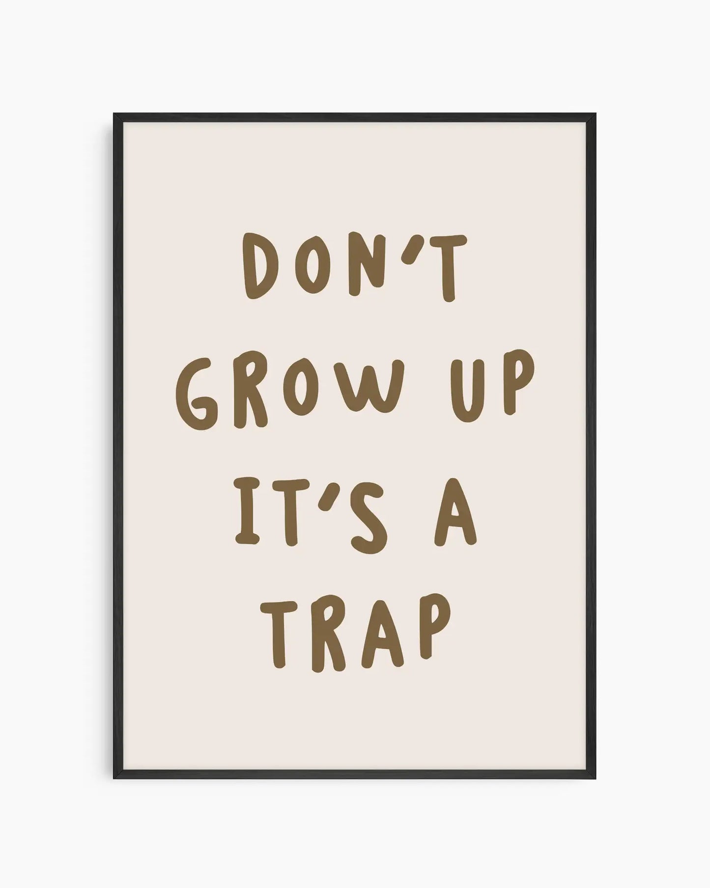 Barntavla med texten “DON’T GROW UP IT’S A TRAP” i bruna bokstäver på ljus beige bakgrund, inramad i svart träram för ett modernt uttryck.
