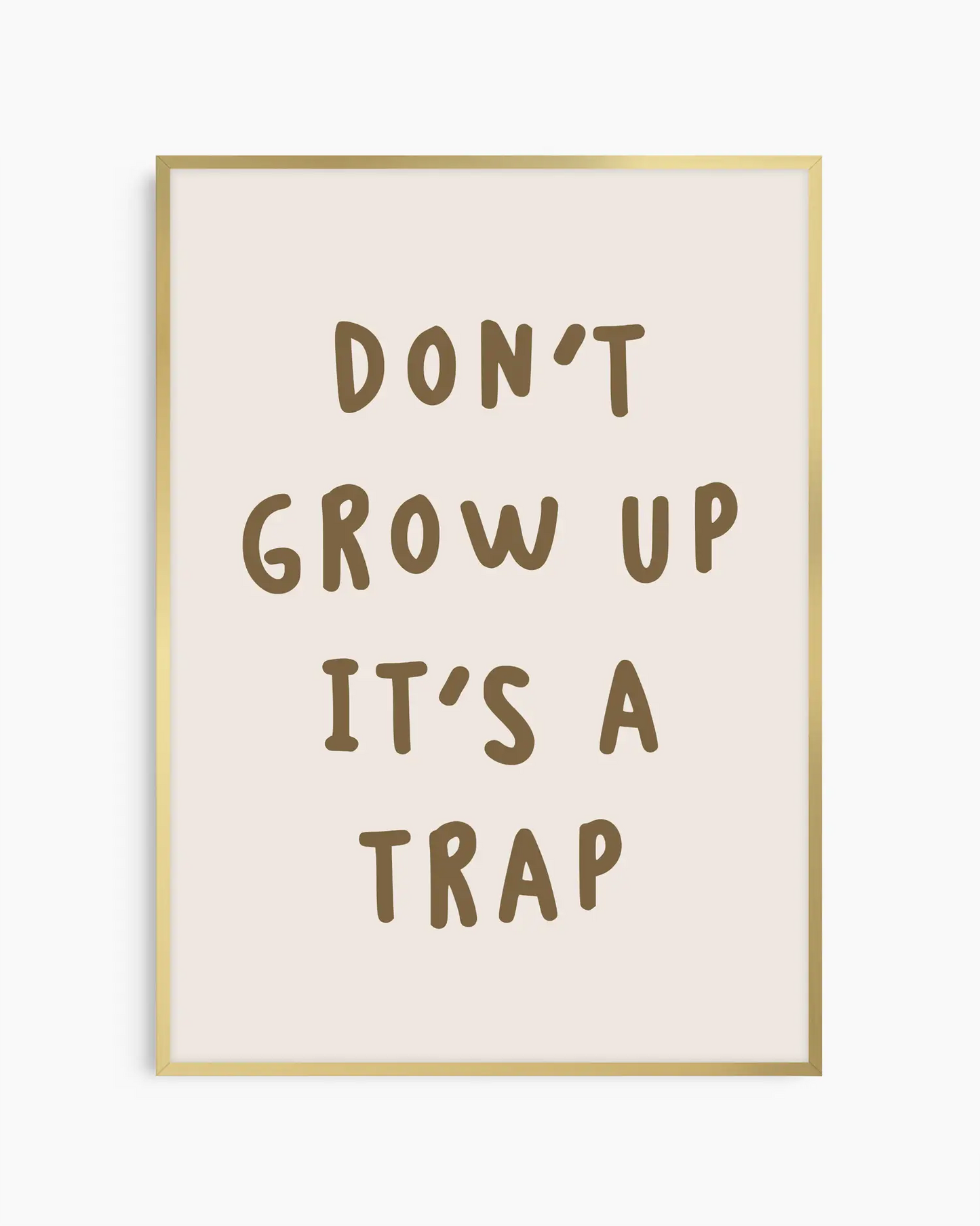 Barntavla med texten “DON’T GROW UP IT’S A TRAP” på beige bakgrund, inramad i guld aluminiumram som tillför en mjuk och elegant kontrast.