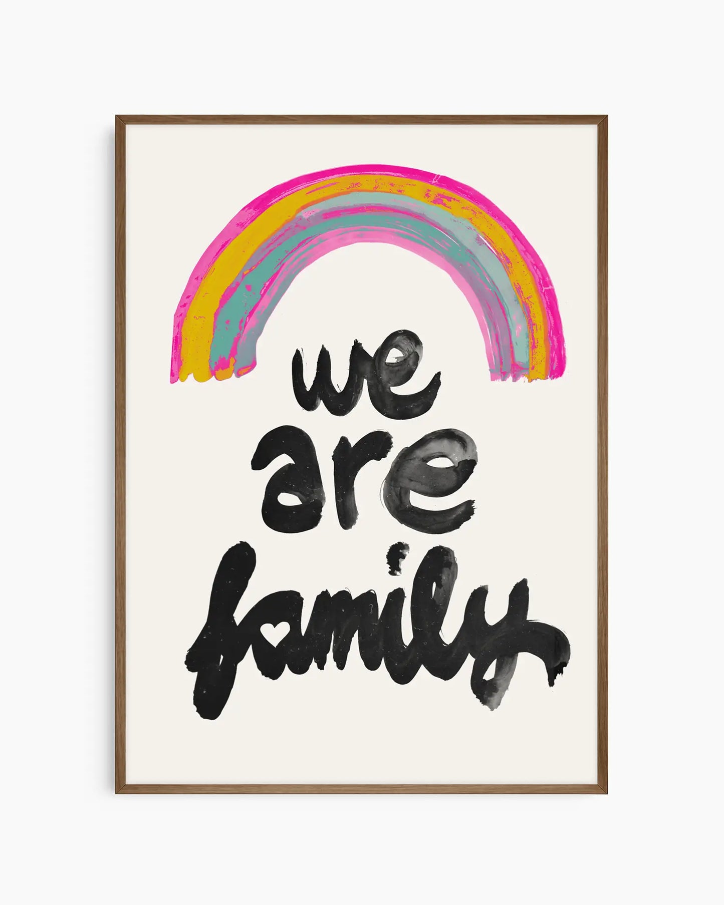 Barntavla med färgstark regnbåge och budskapet "WE ARE FAMILY", inramad i mörk ekram som skapar en mjuk kontrast mot den ljusa bakgrunden.