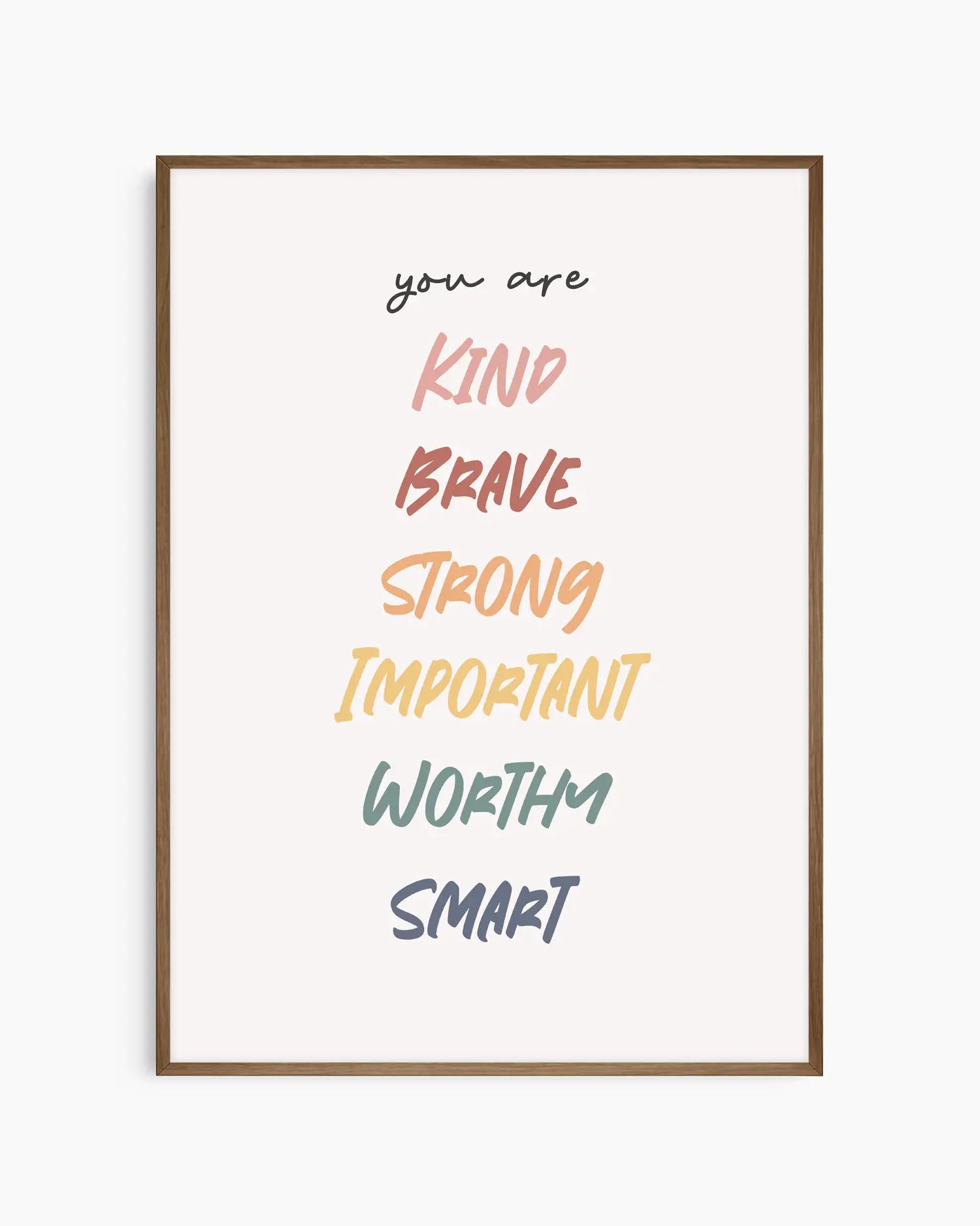 Barntavla med inspirerande ord i olika nyanser och texten "you are KIND BRAVE STRONG IMPORTANT WORTHY SMART", inramad i mörk ekram. En varm och motiverande detalj för barnrummet.