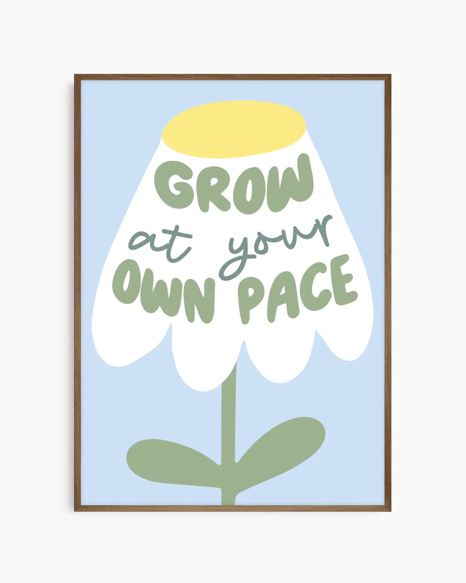 Barntavla med stiliserad blomma och texten "GROW AT YOUR OWN PACE" på ljusblå bakgrund, inramad i mörk ekram. En harmonisk och inspirerande detalj för barnets rum.
