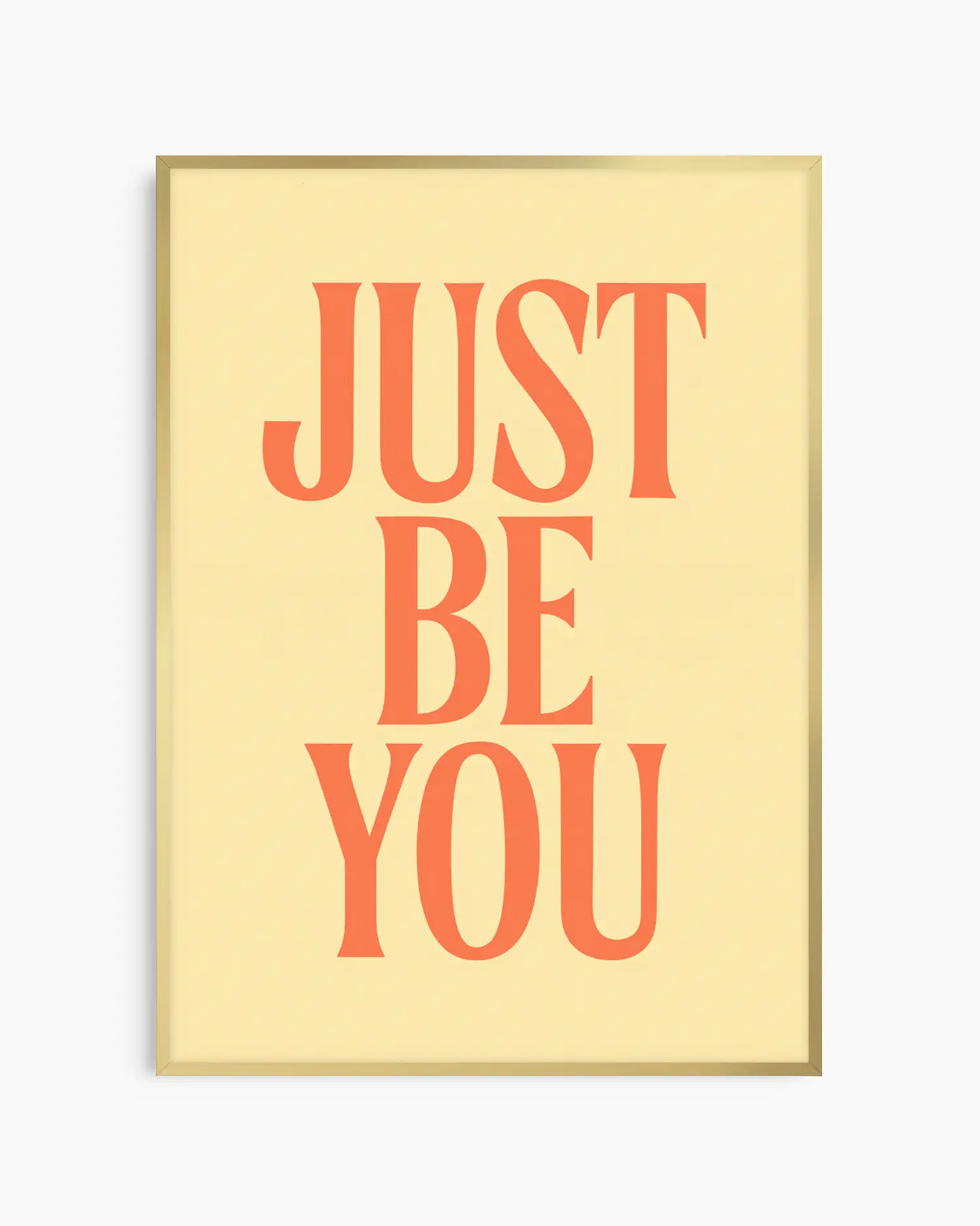 Barnrumstavla med texten "JUST BE YOU" i orange på ljus gul bakgrund, inramad i guld aluminiumram. En elegant och inspirerande väggdetalj.