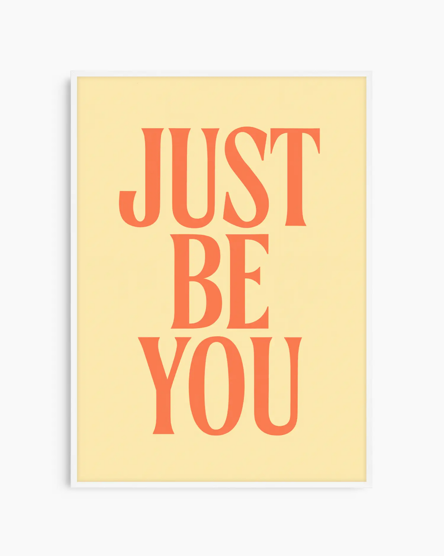 Barnrumstavla med texten "JUST BE YOU" i orange, placerad på mjuk gul bakgrund och inramad i vit träram. En ljus och inspirerande väggdekoration.