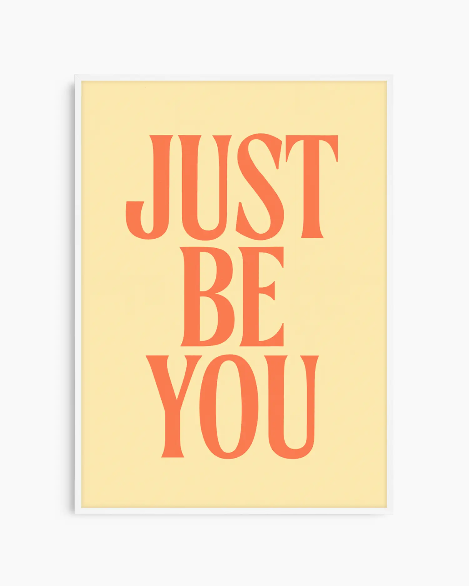 Barnrumstavla med texten "JUST BE YOU" i orange, placerad på mjuk gul bakgrund och inramad i vit träram. En ljus och inspirerande väggdekoration.
