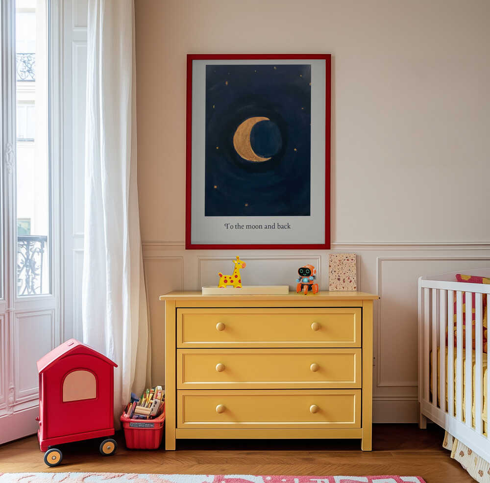 Inramad barntavla med halvmåne och texten ”To the moon and back” hängandes ovanför den gula byrån och skapar en varm, drömsk detalj i barnrummet.