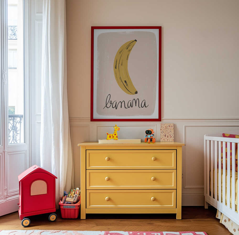Inramad barntavla med bananillustration hängandes ovanför den gula byrån och tillför rummet en lekfull och glad atmosfär.
