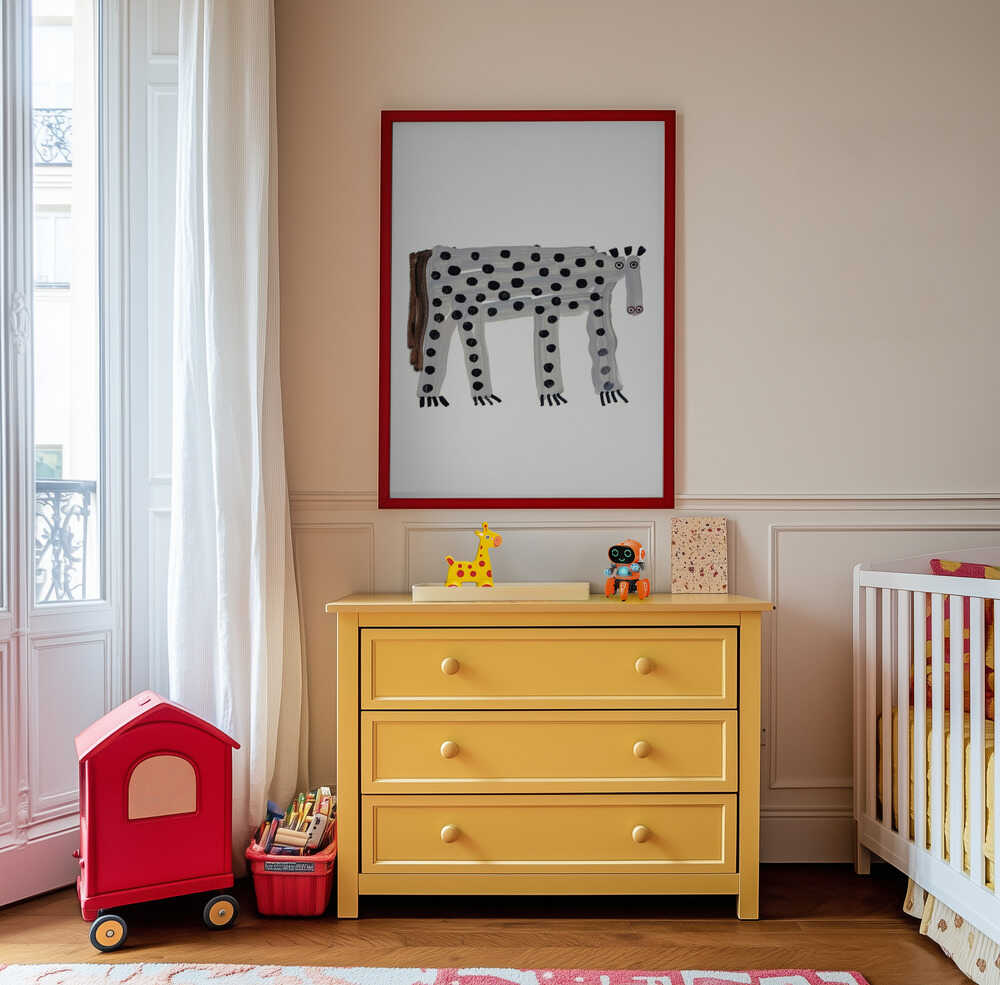 Inramad barntavla med prickigt fantasidjur som hänger ovanför den gula byrån och tillför rummet färg, humor och kreativitet.